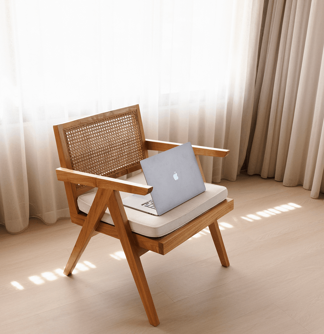 a laptop on a wooden chair in a cream room with cream curtains