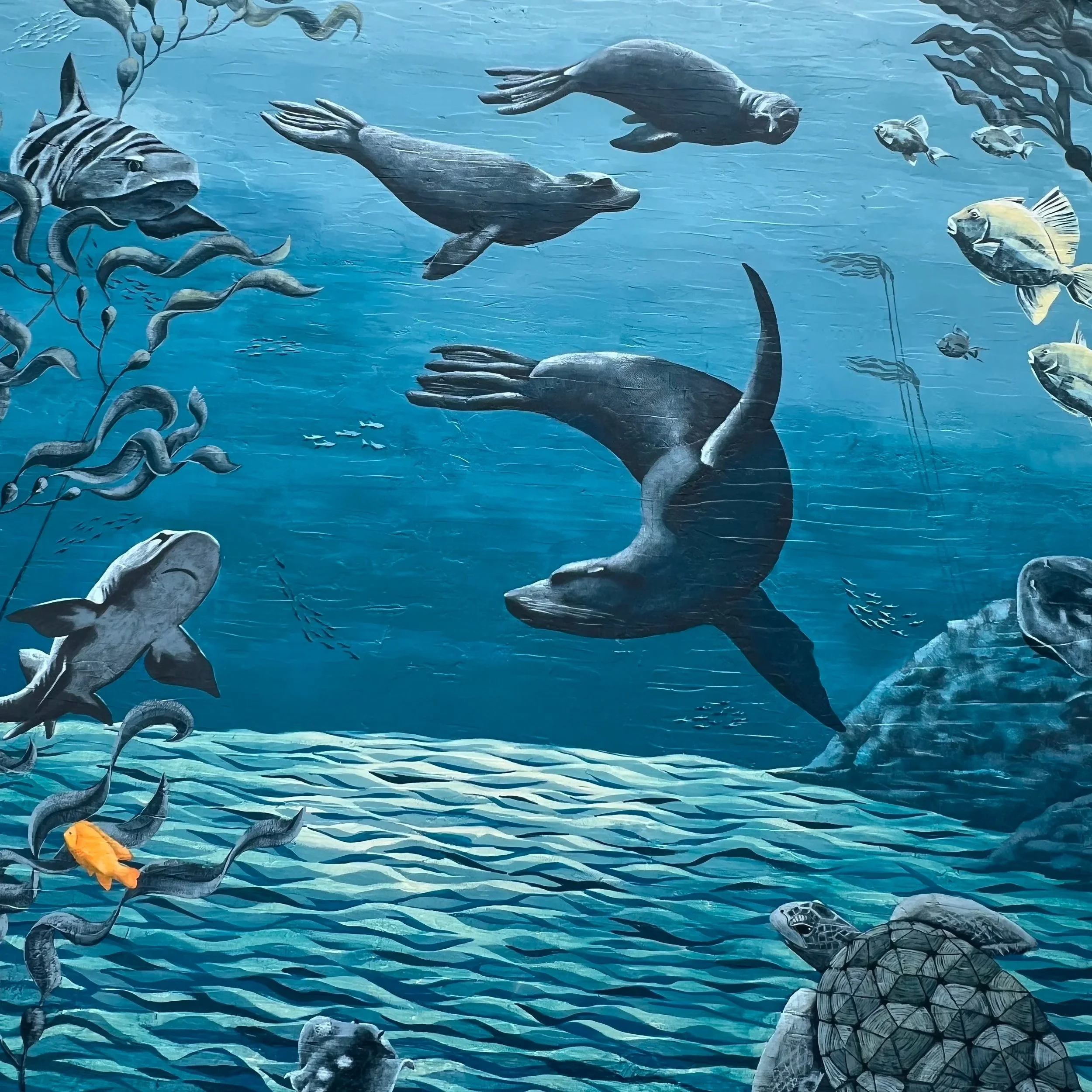 Close-up of sea lions and fish in the sculptural relief of the Teeming with Life mural