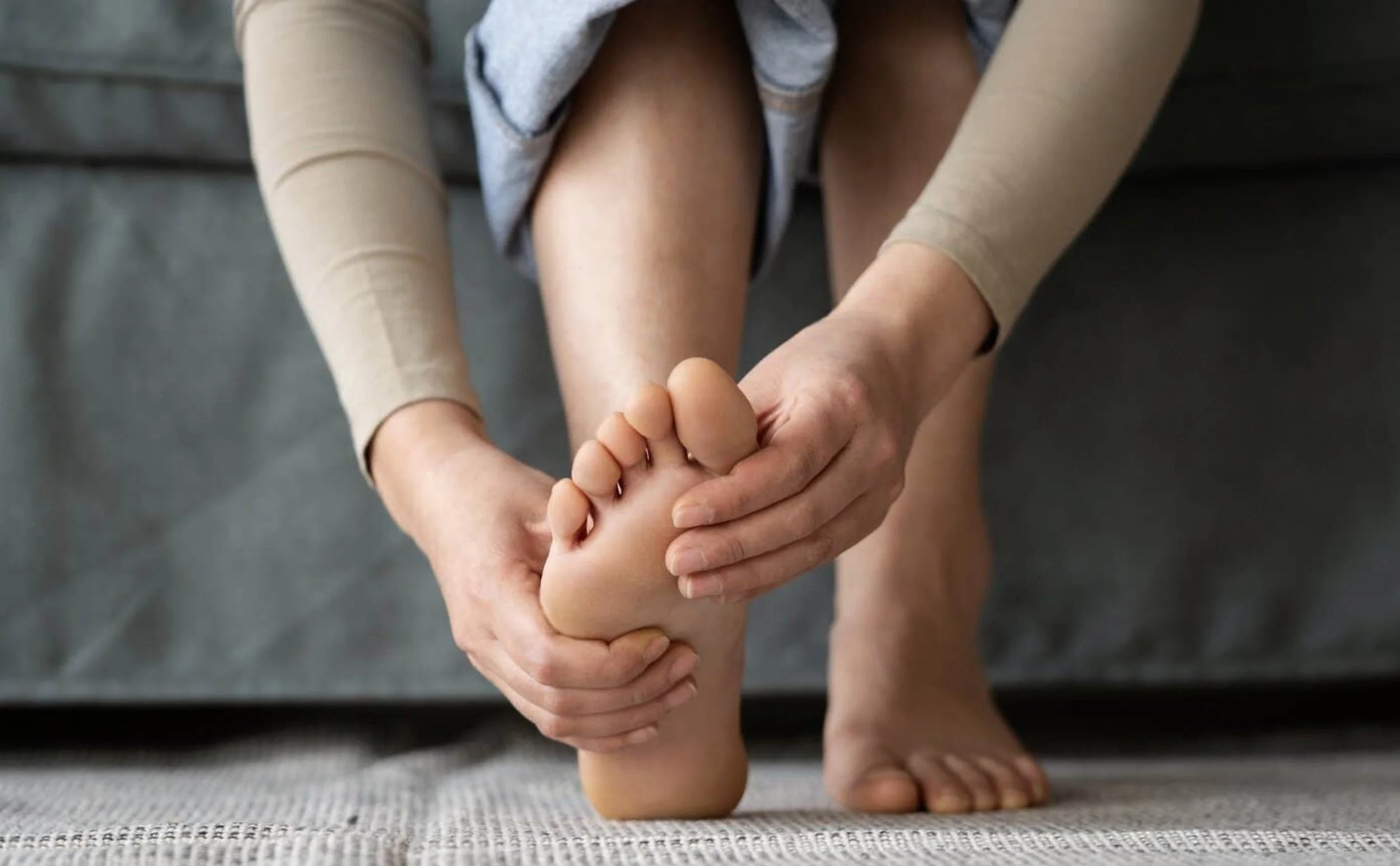 Person holding the bottom of their foot due to plantar fasciitis and heel pain.