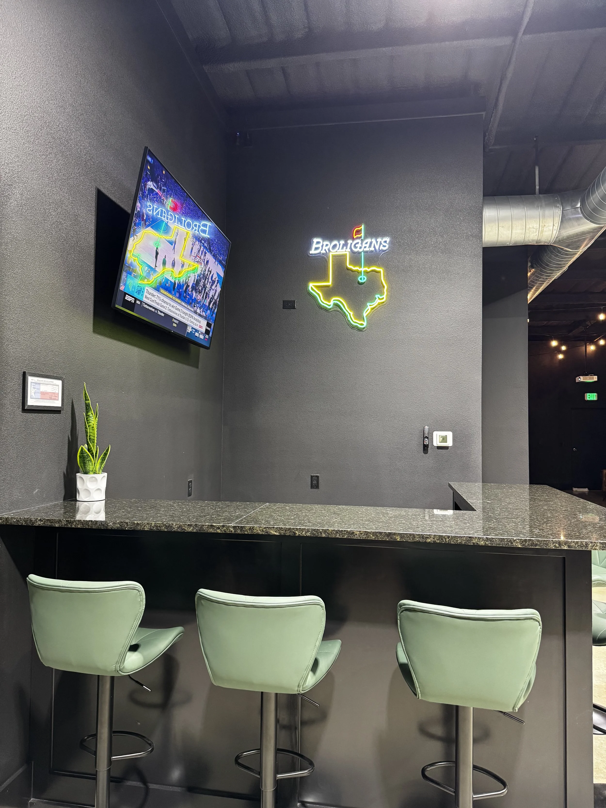 Broligans Bar with its famous neon Texas golf sign above the bar seating area with TV and barstools.