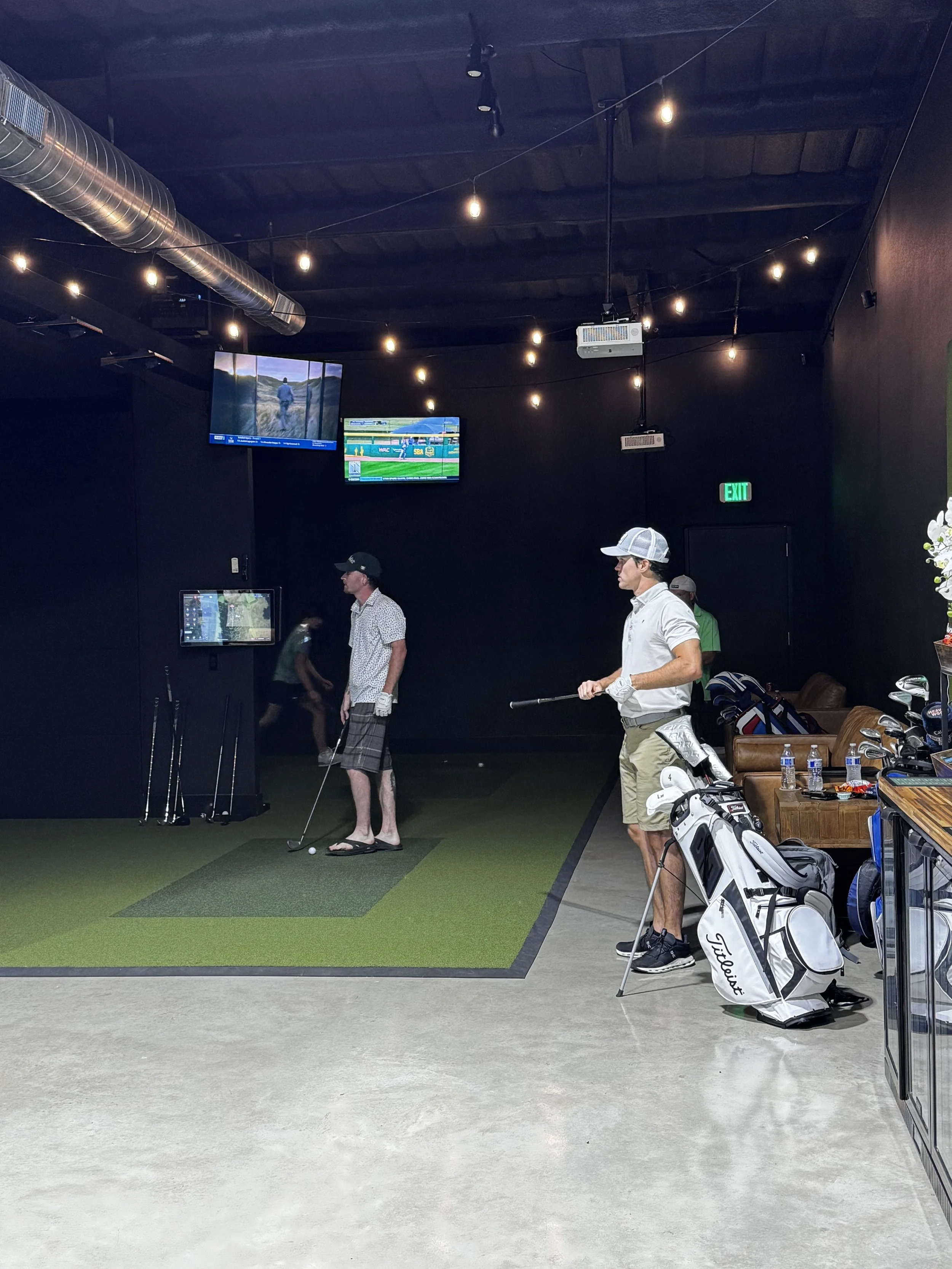 Friends playing indoor golf simulators together at Broligans in Brock, Texas