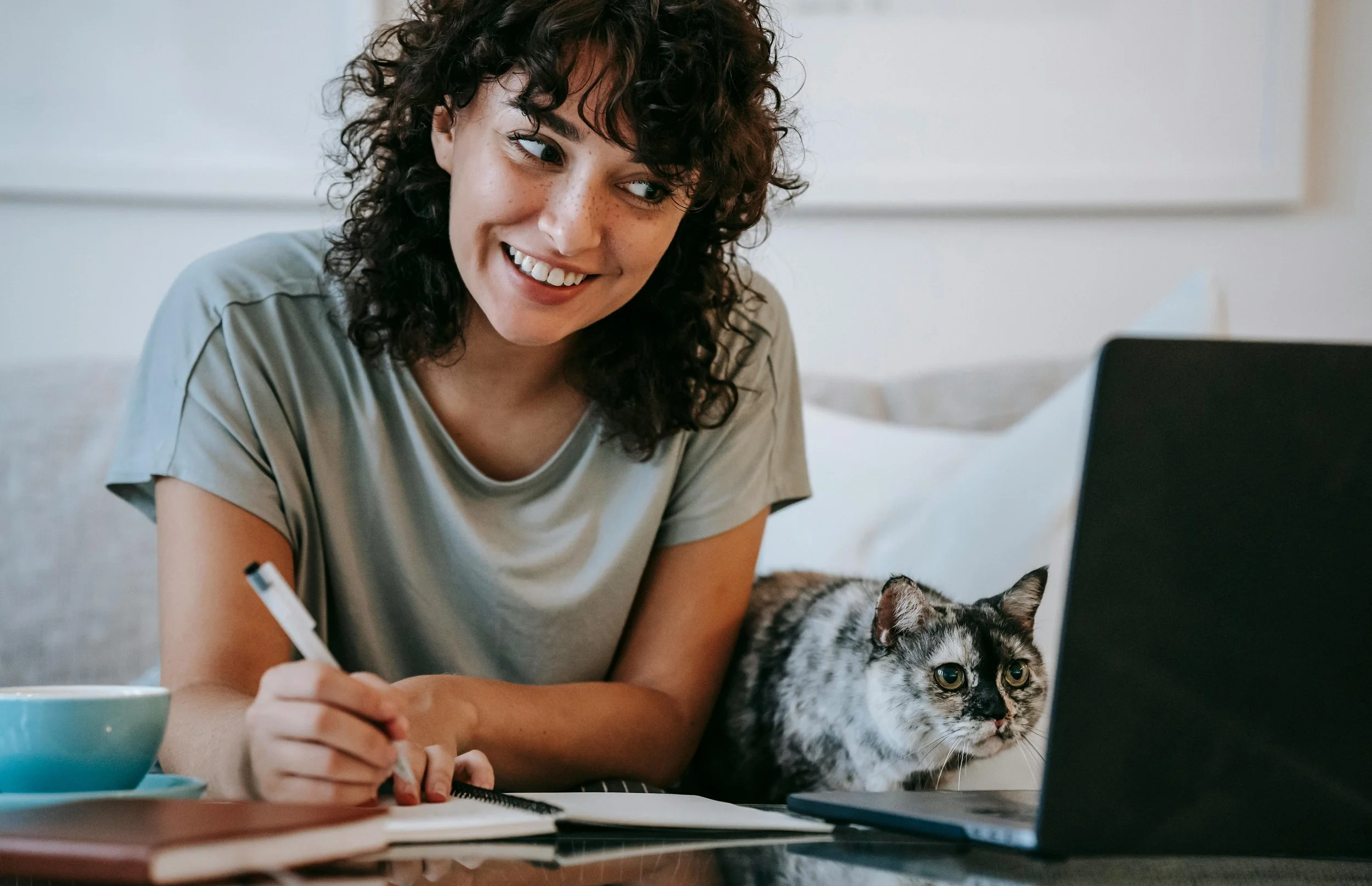 Photo of woman working from home with her cat beside her