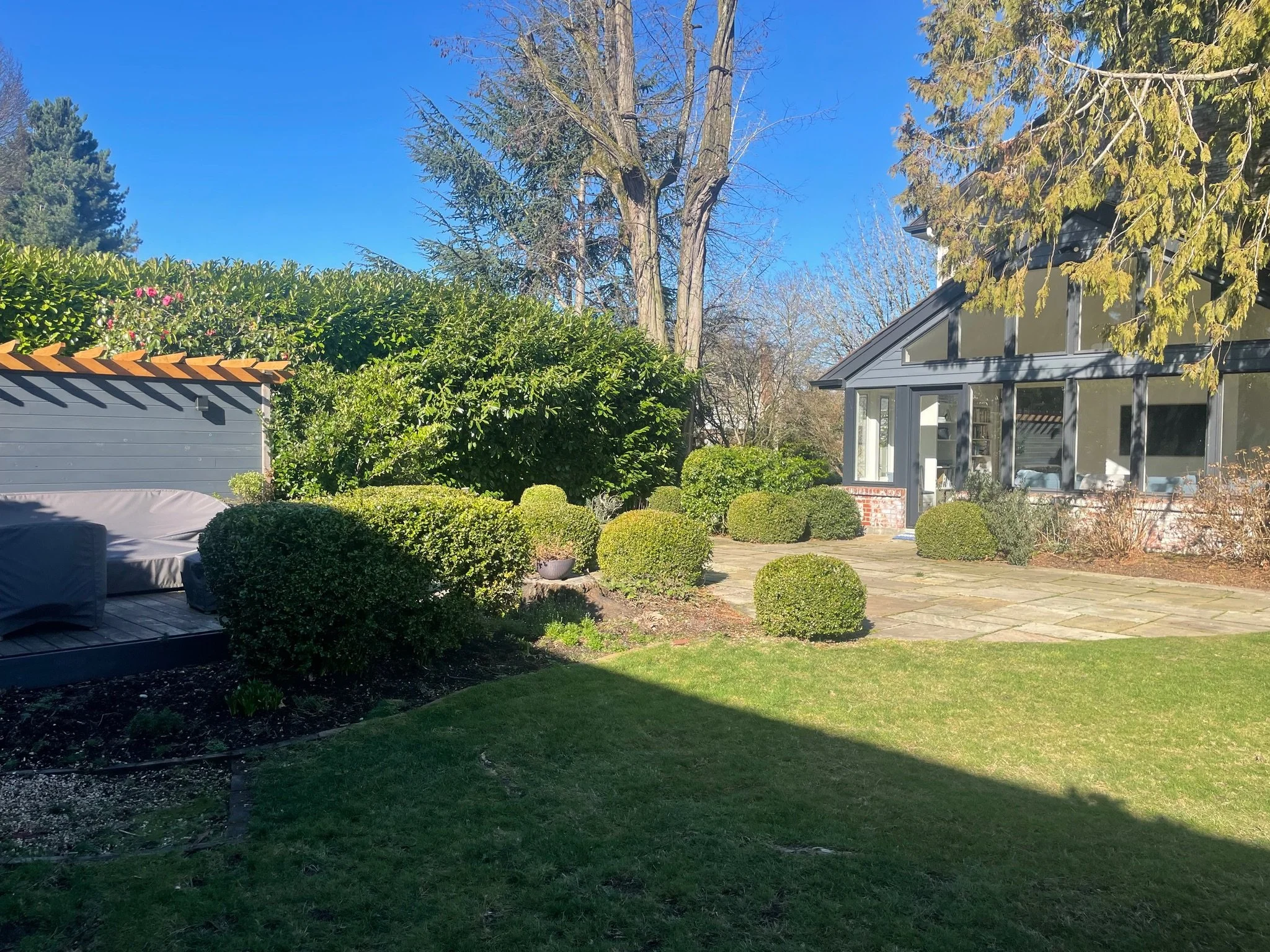 The outdoor living space felt awkward and disconnected, with scattered sheared boxwoods, a curved heaving patio, and a small deck oddly placed.