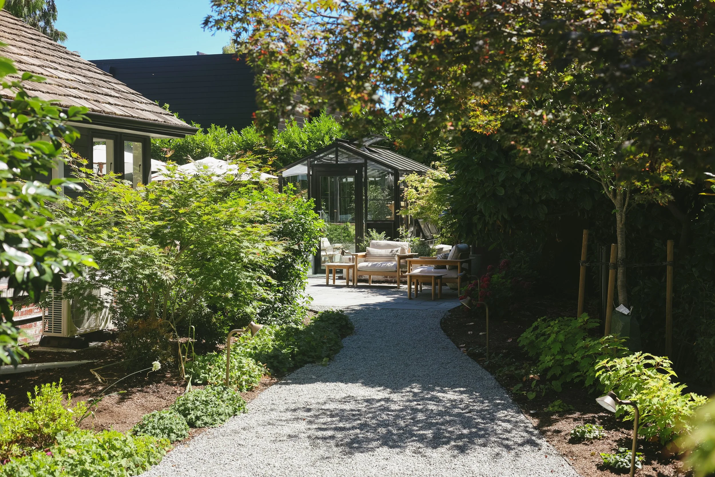 Brand new trees frame the view of the greenhouse and layered plantings help to complete this path.
