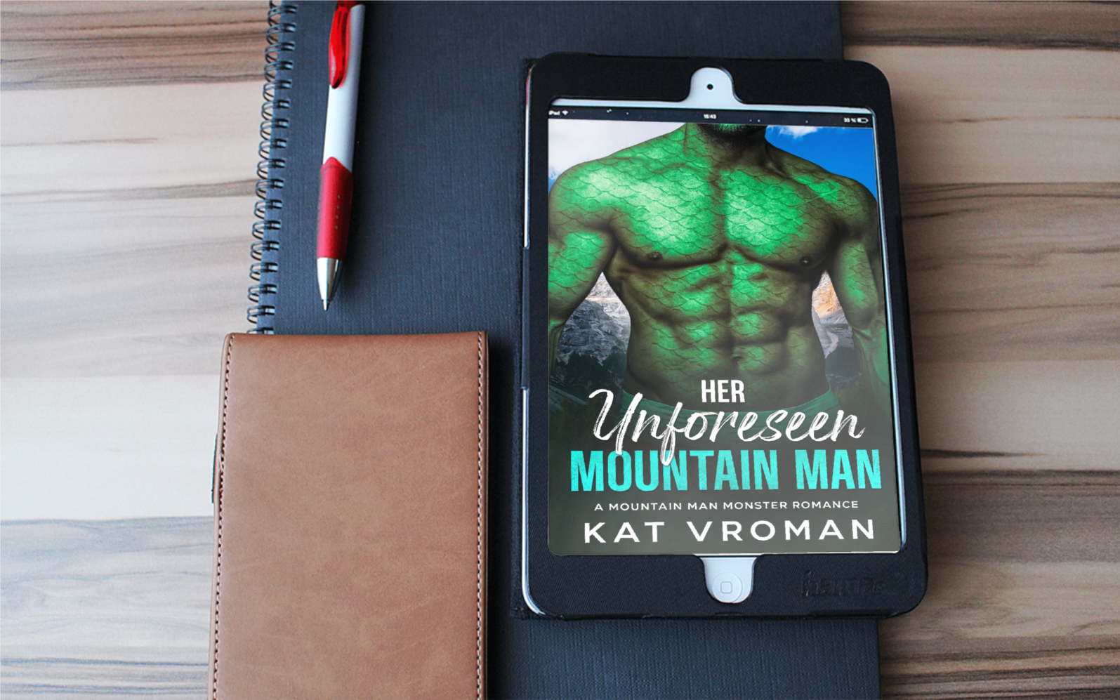 Her Unforeseen Mountain Man by Kat Vroman on tablet, pen, black notebook, leather small notebook