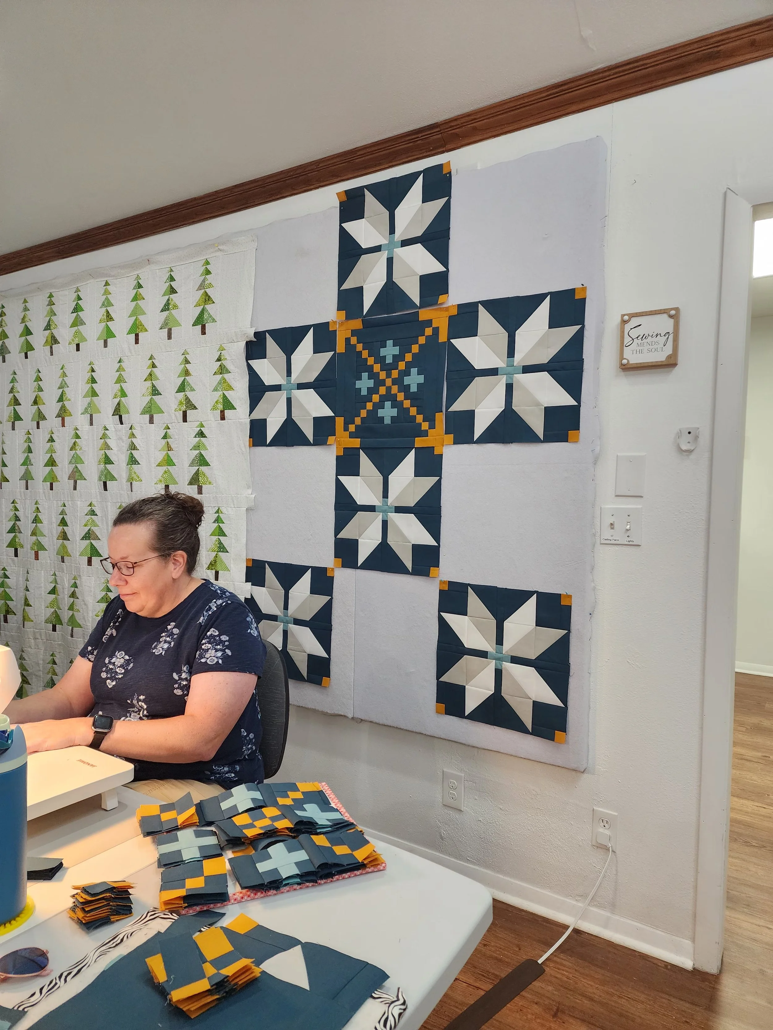 Tina sewing with her quilt top on the wall