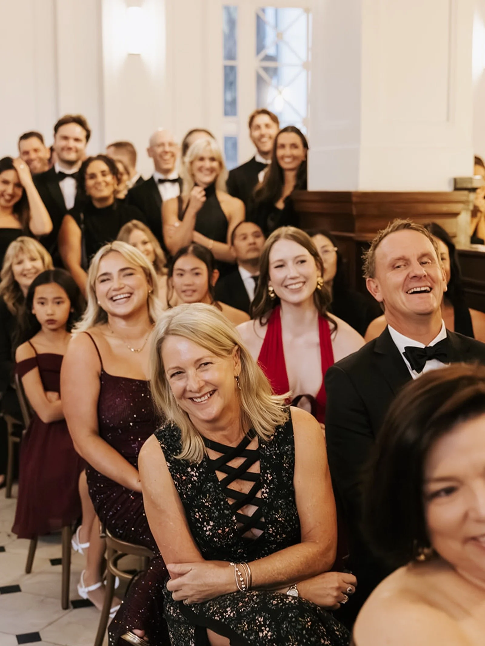 Group of people dressed in formal attire at a celebration or event, smiling and posing for the photo indoors.