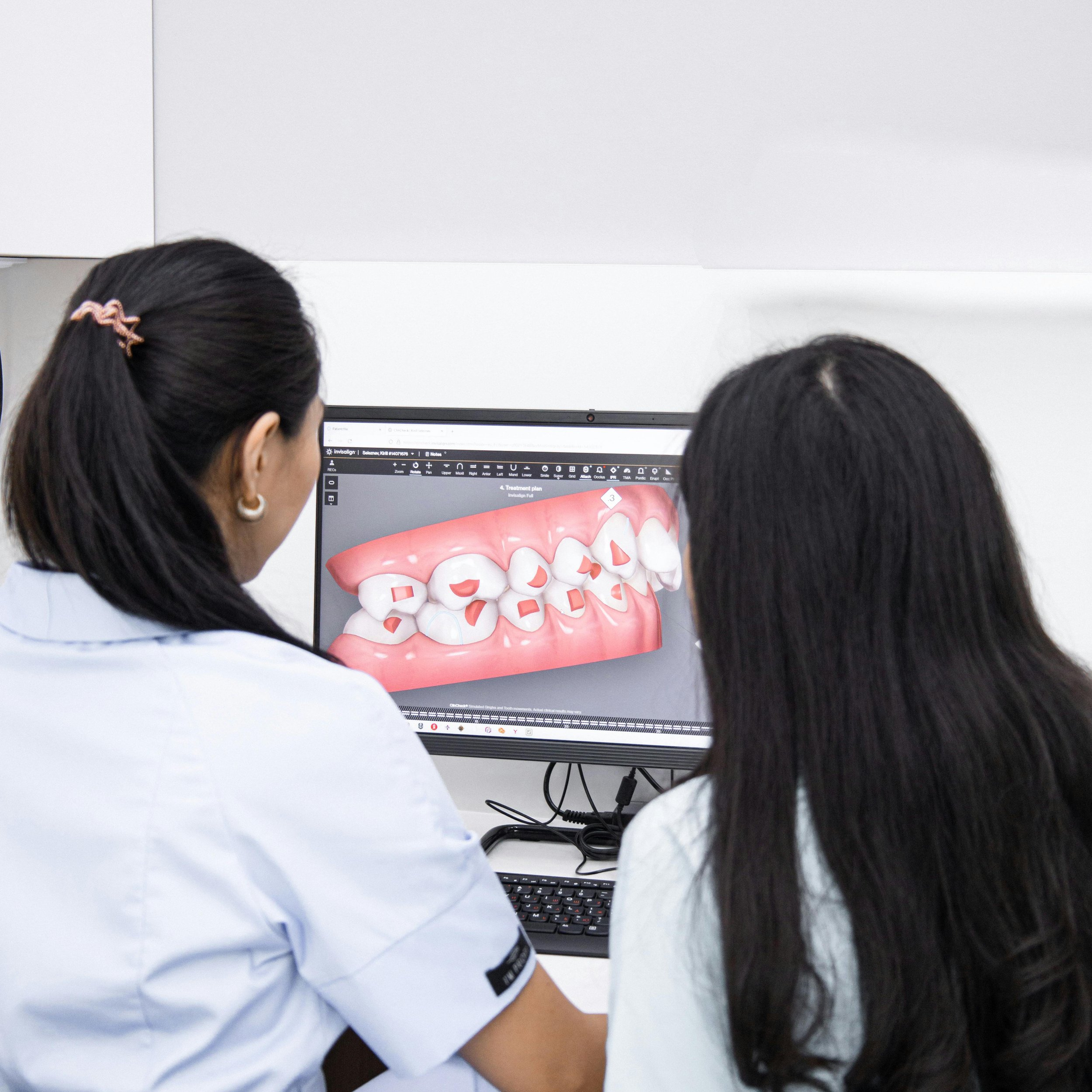 Two clinicians reviewing a clear aligner treatment plan on screen