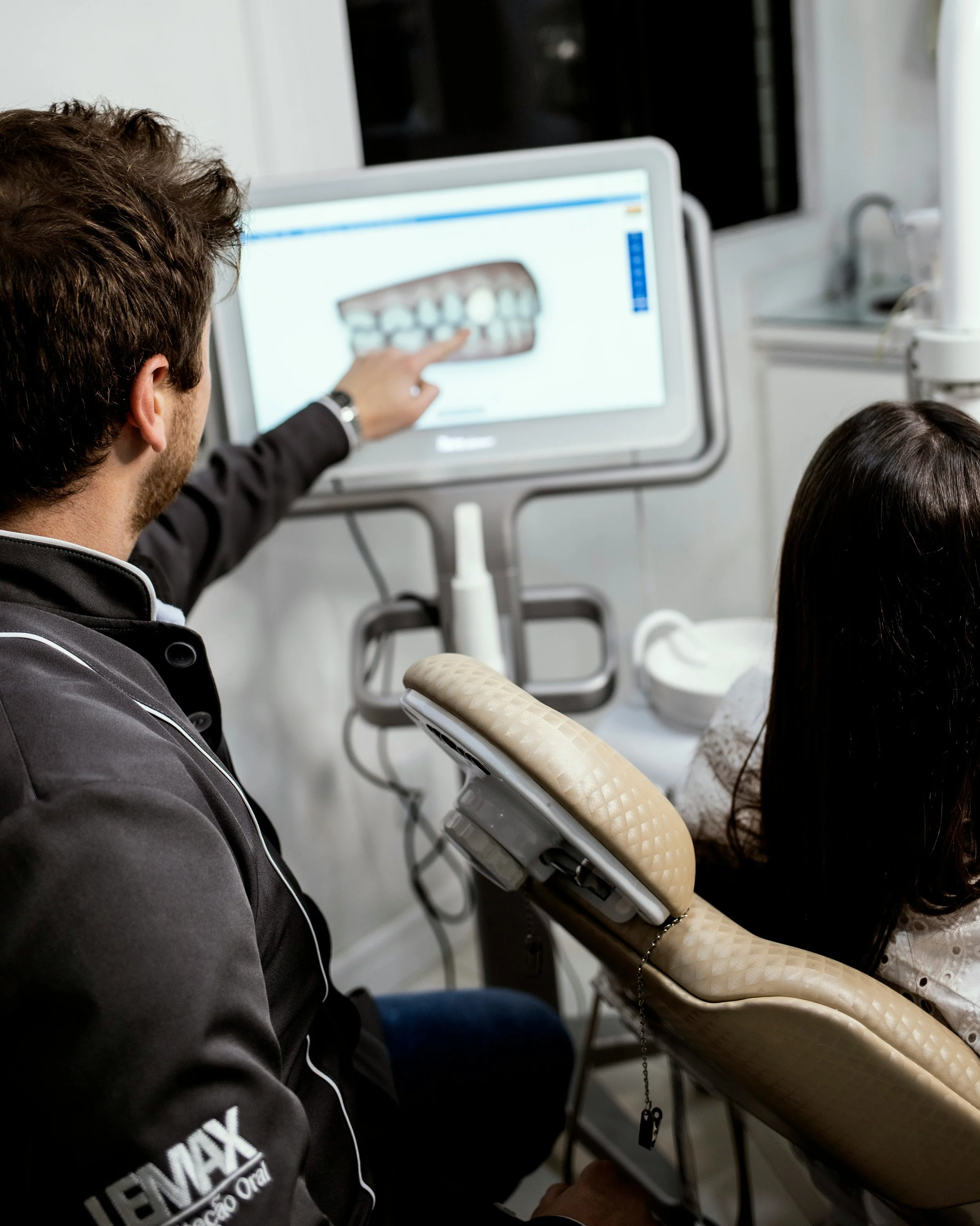 Dentist explaining a treatment plan on a computer screen to a patient in a dental office.