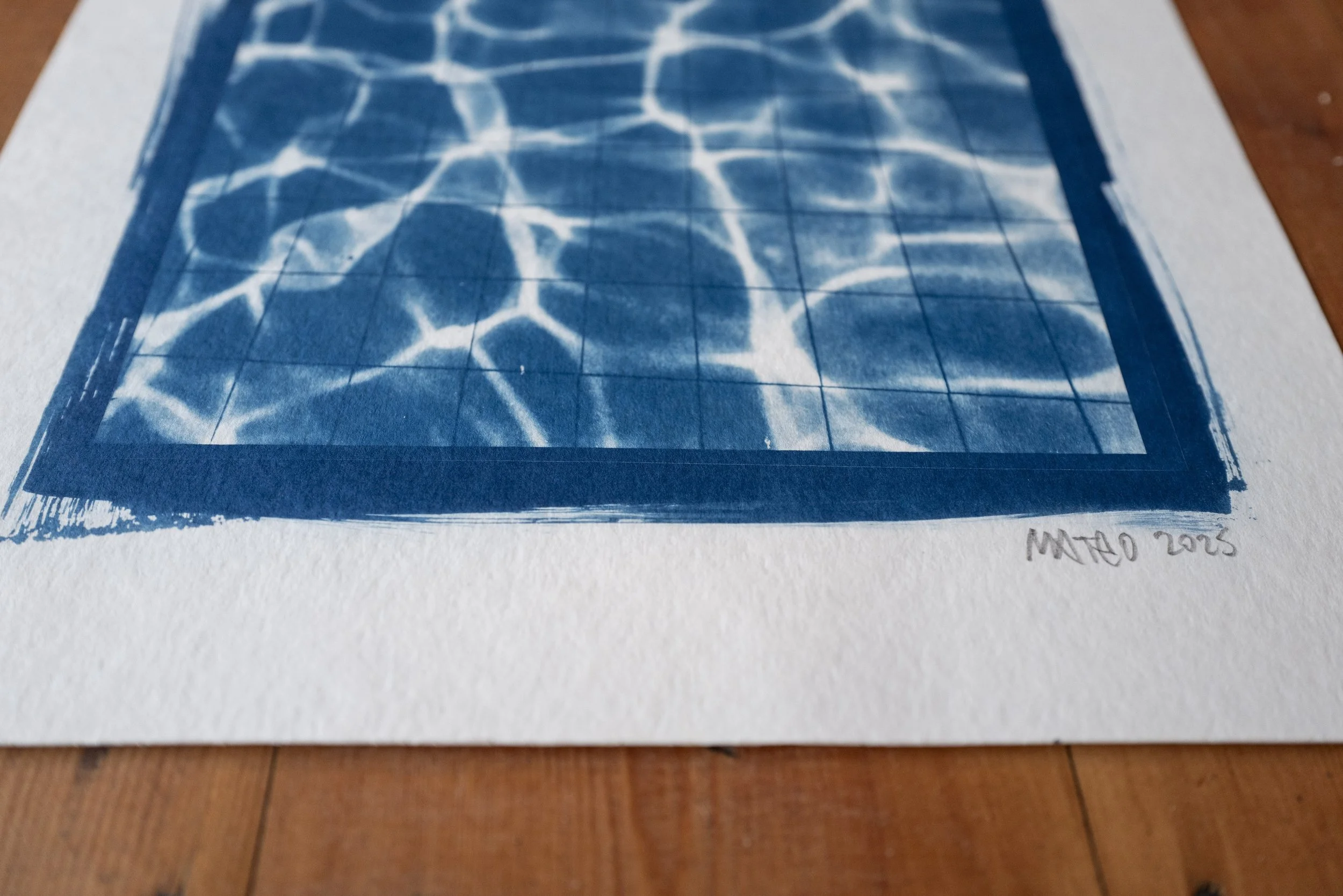 A blue and white cyanotype print of water ripples on a tiled floor, with the artist's signature 'Mateo 2025' in the bottom right corner.