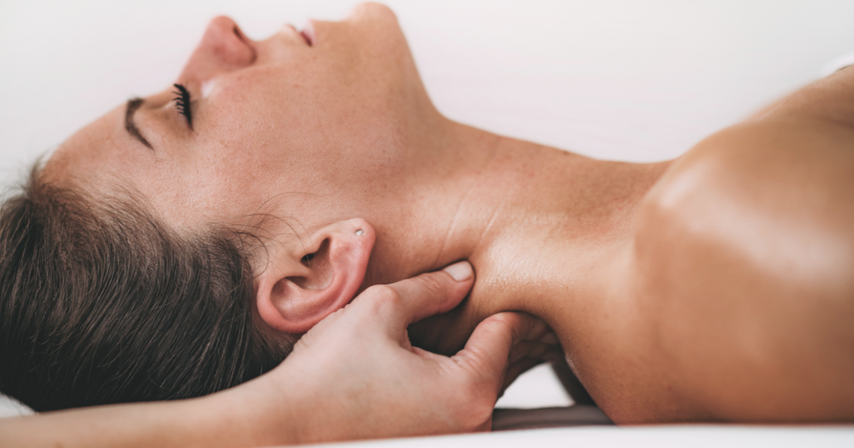 Woman receiving therapeutic neck massage with focused pressure below the ear and along the side of the neck.