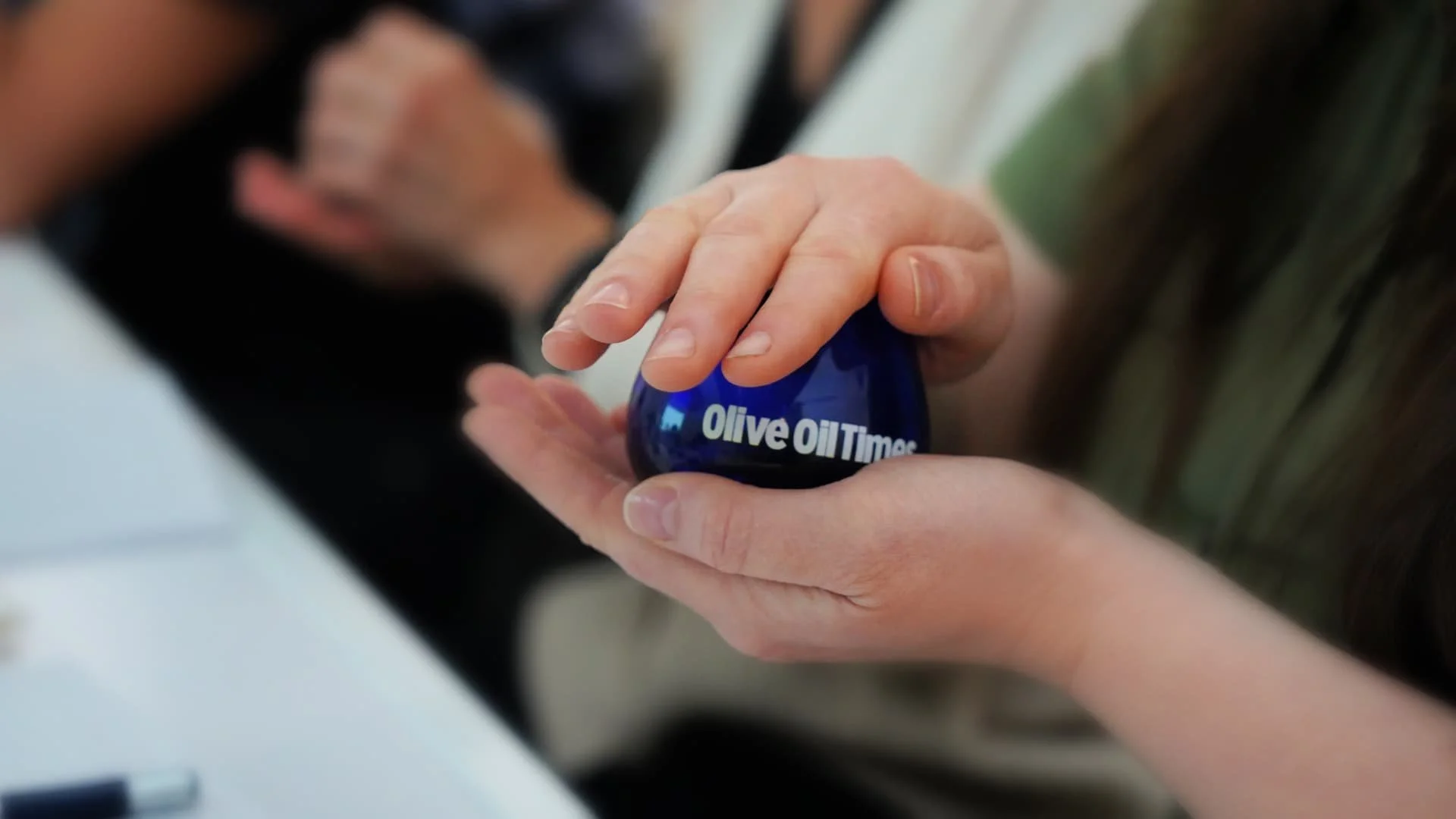 a person holding a professional blue glass and warming up the olive oil