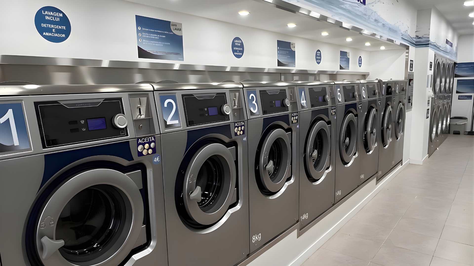 Lavandaria self-service moderna, equipada com várias máquinas de lavar roupa e secadores profissionais alinhados e numerados.