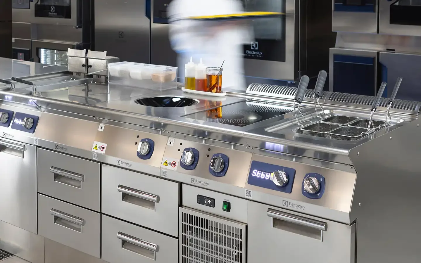 Linha modular de confeção Electrolux Professional e-XP 700/900 em inox, com placa de indução, cuba circular integrada e fritadeira, num ambiente de cozinha profissional.