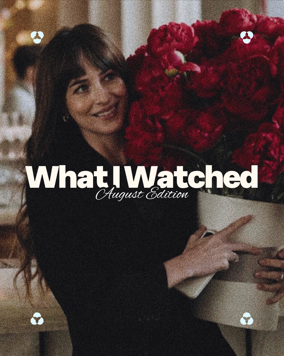 A woman with long dark hair holding a large bouquet of red flowers, smiling in a dimly lit indoor setting.