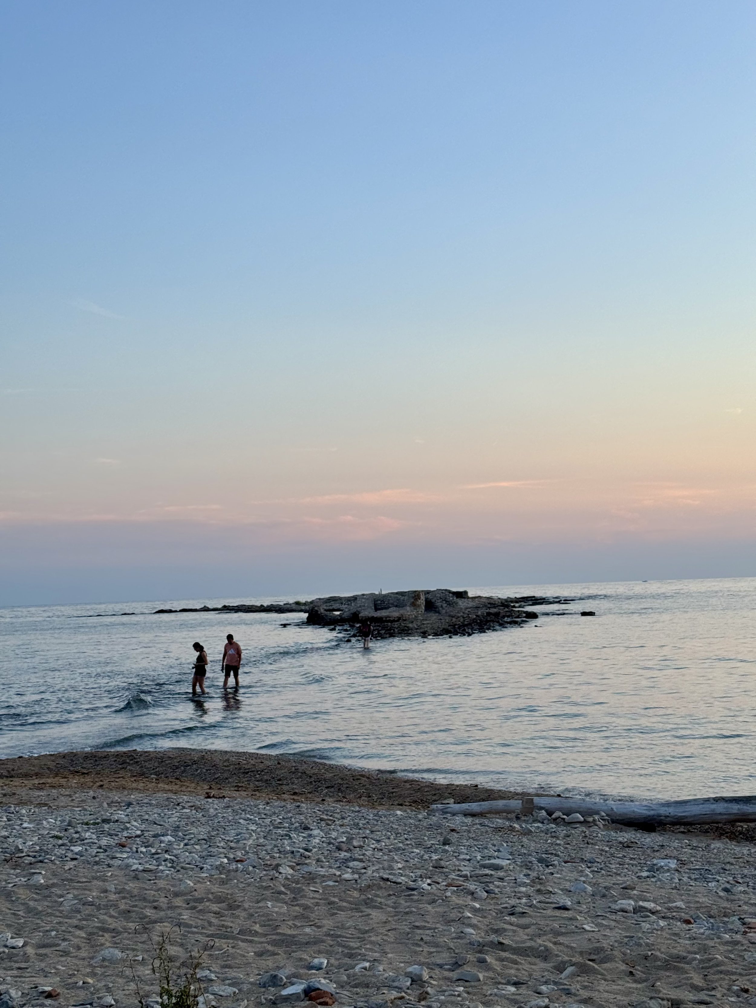 Couple walking hand in hand along a quiet Adriatic shoreline at sunset