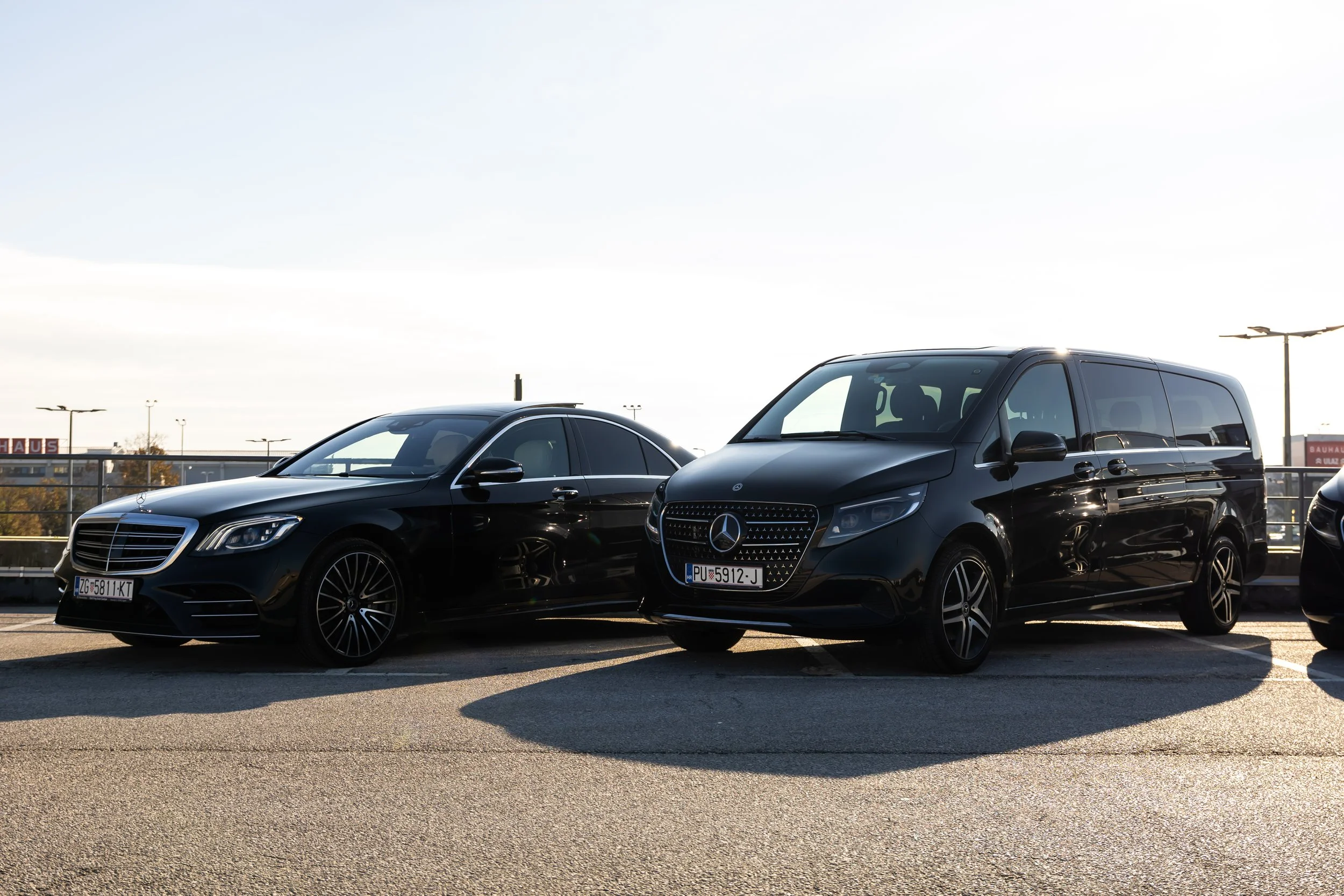 Professional security-trained chauffeur standing by a black Mercedes-Benz S-Class for diplomatic protocol service.