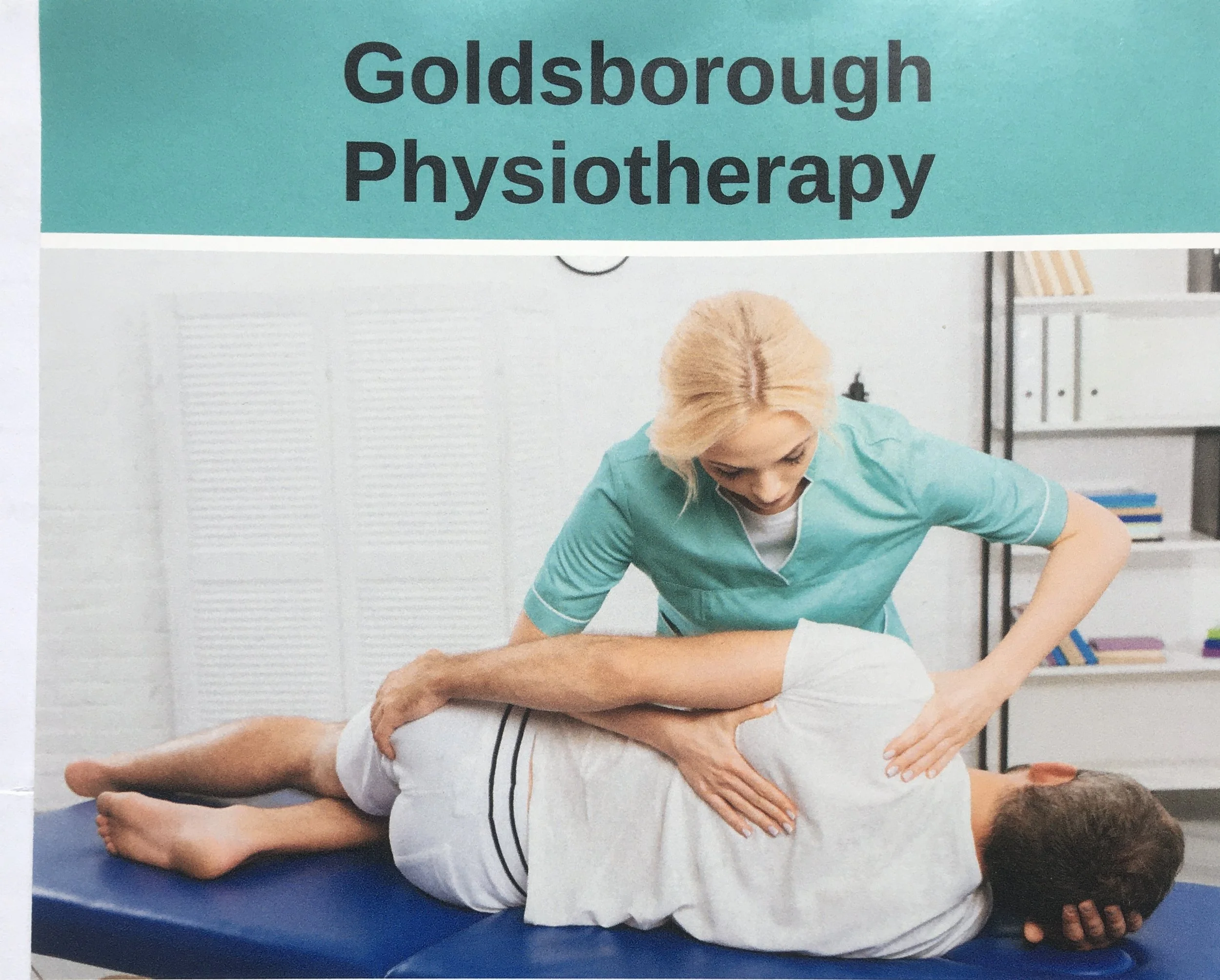 A physical therapist performing spinal therapy on a patient lying face down on a treatment table in a medical office.