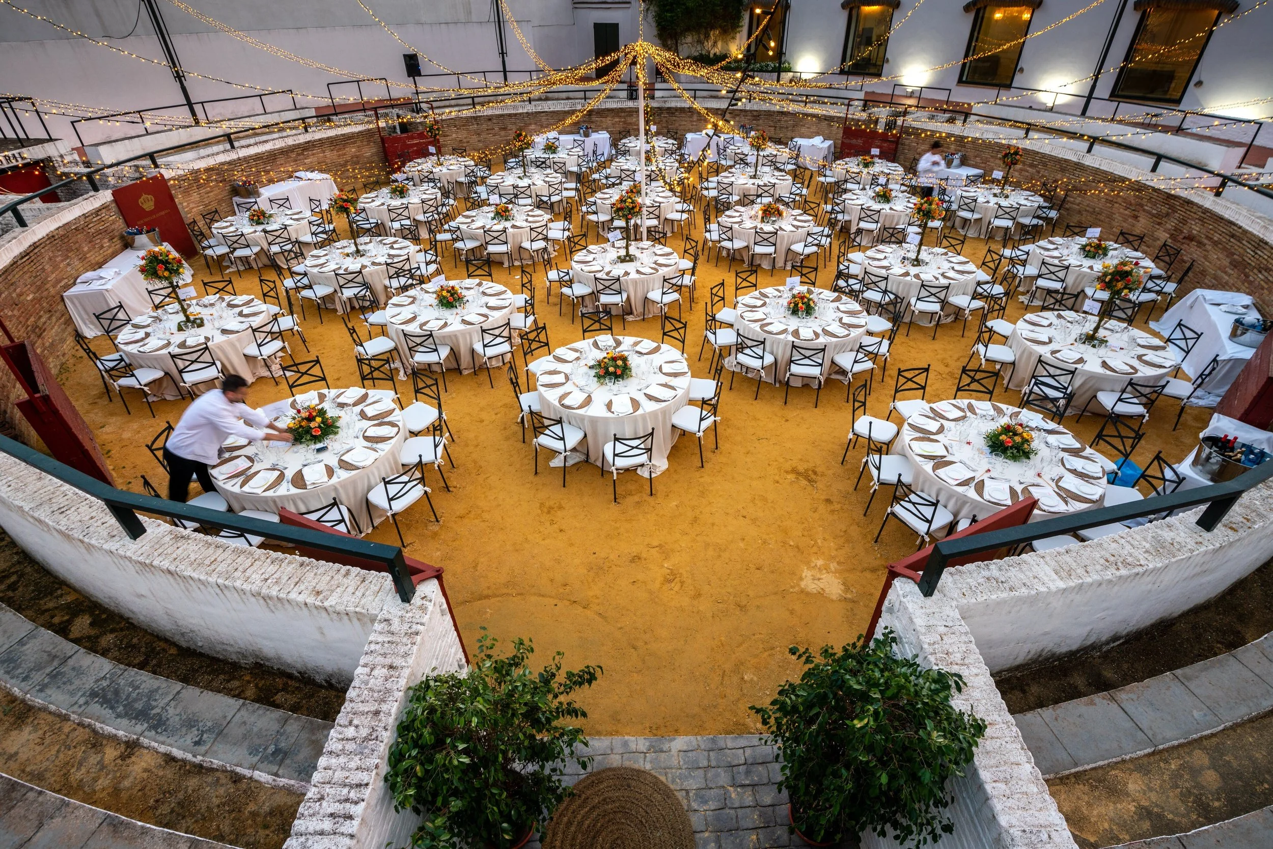 Aerial view of wedding reception in bullring at night event decorated with lights.