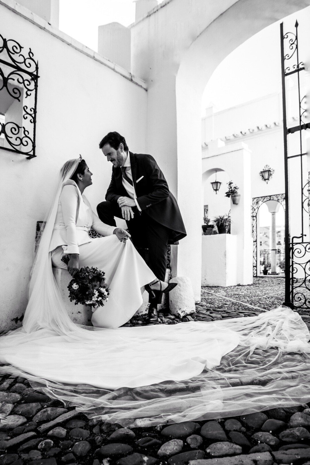 Bride and groom posing in black and white photo in charming corner of wedding venue