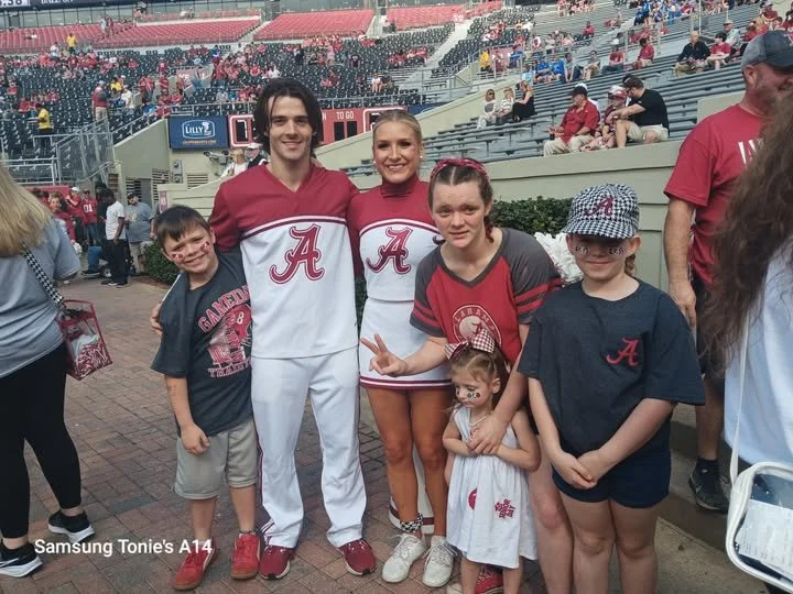 Crimson and family get a photo with Alabama cheerleaders