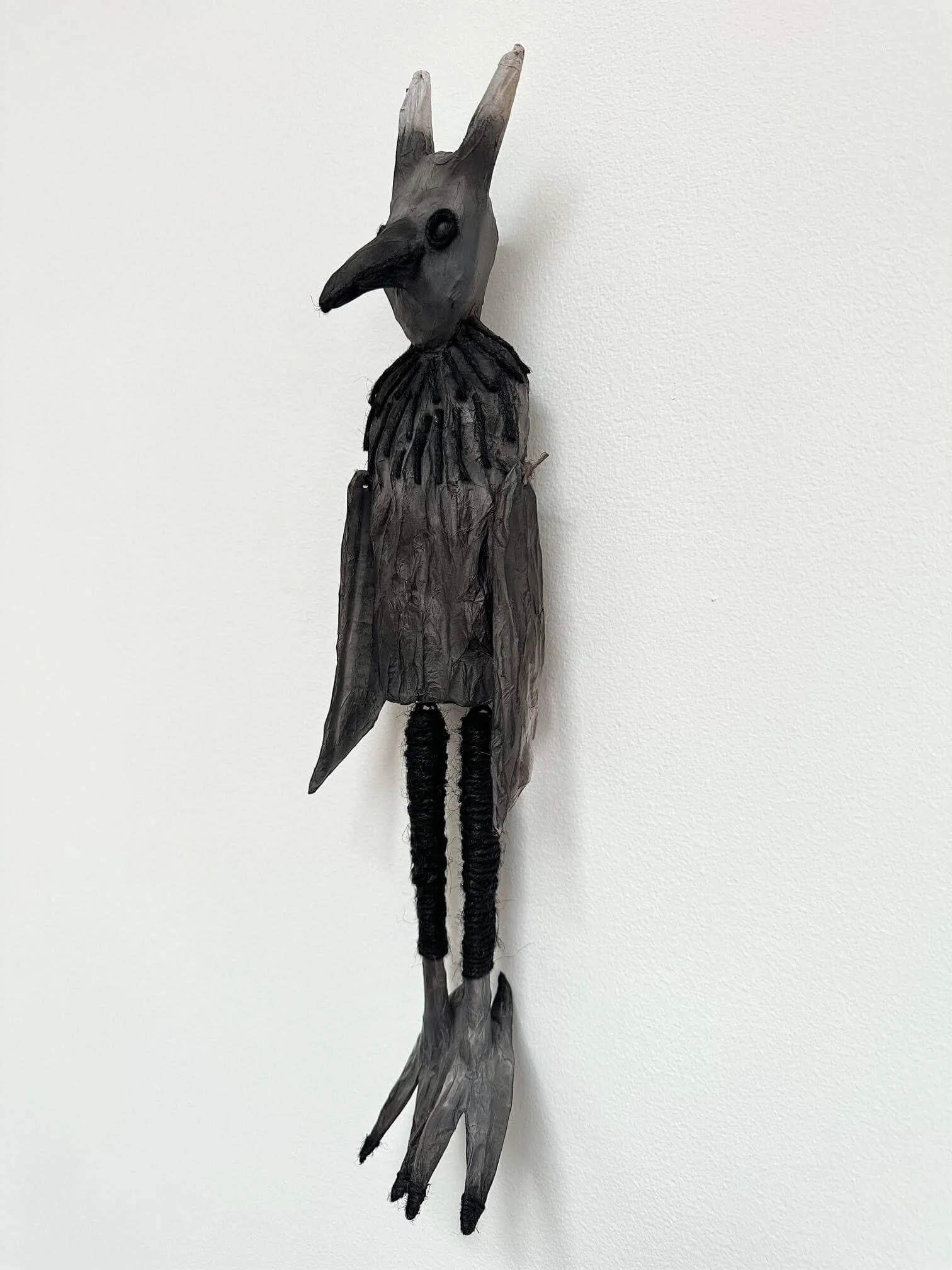 Crow Creature paper sculpture hanging on wall