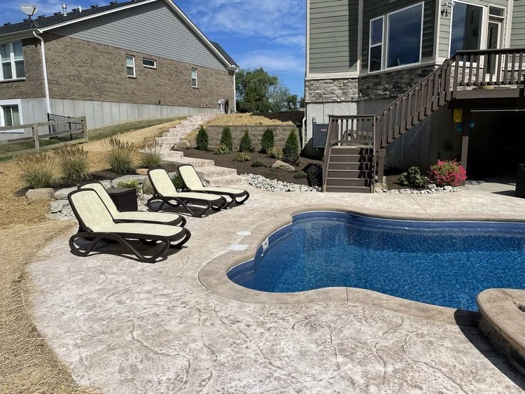 Backyard with a small swimming pool, three lounge chairs, and a house with stairs leading to a deck.