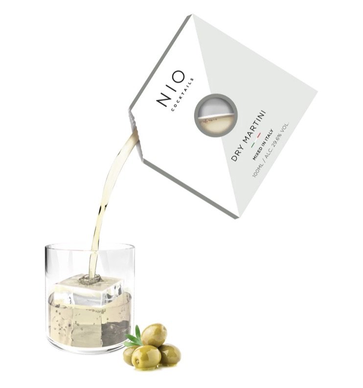 NIO Cocktails Dry Martini being poured into a glass with a large ice cube, accompanied by green olives.