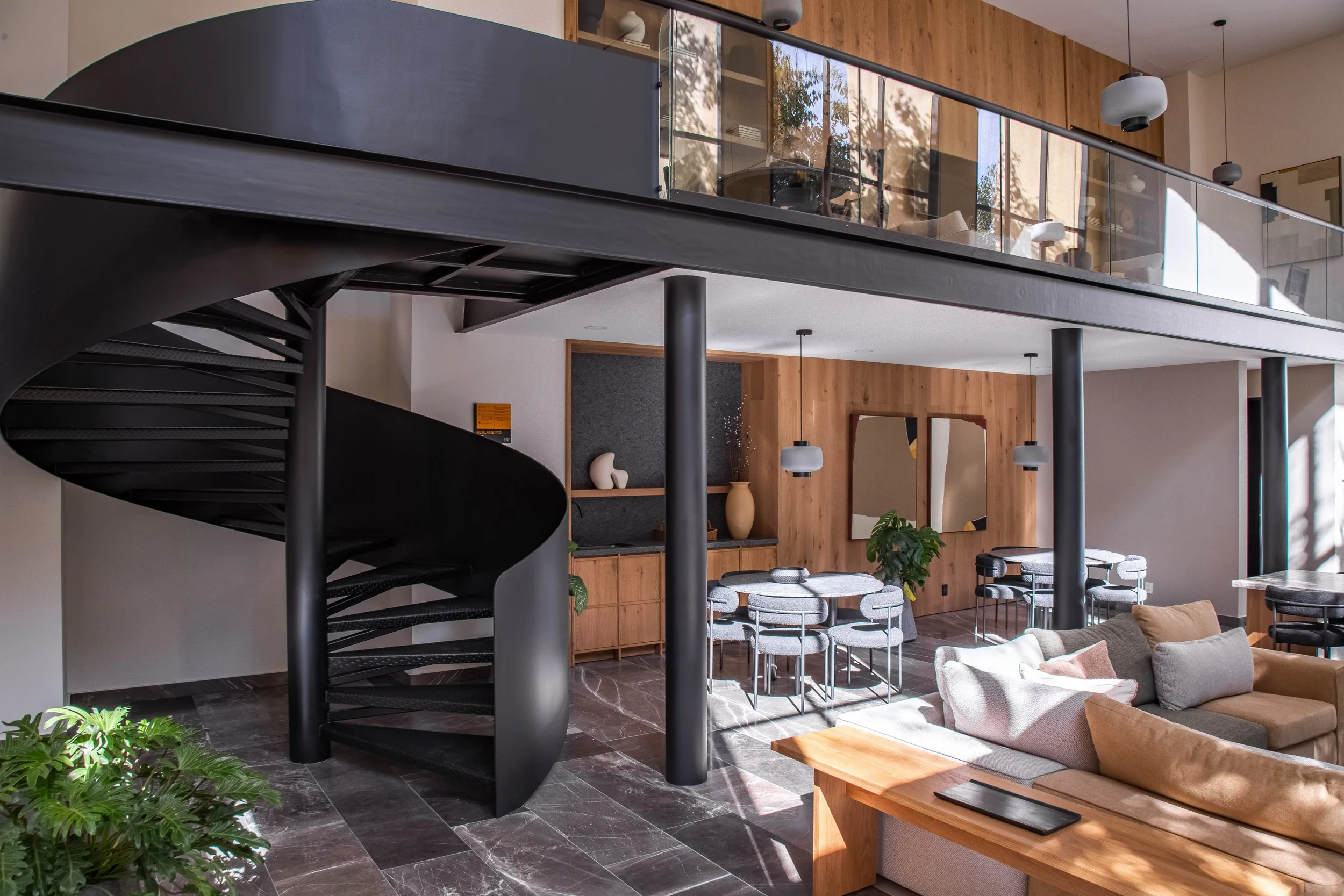 Interior de una casa moderna con escaleras en espiral negras, áreas de descanso con sillones y mesas, paredes de madera, decoraciones minimalistasy plantas