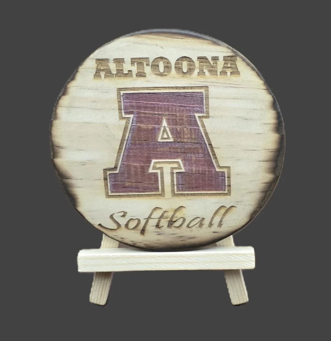 A wooden plaque with the words 'ALTOONA Softball' engraved on it, featuring a large letter 'A' in the center, displayed on a small wooden easel.