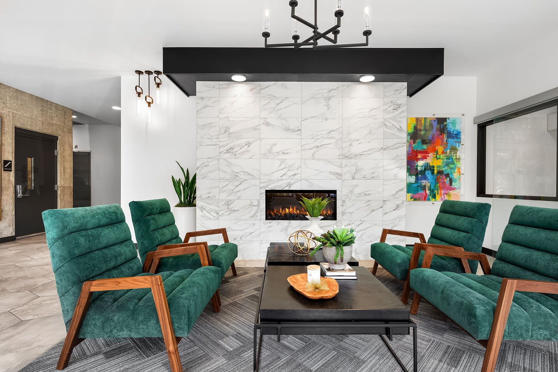 An apartment complex lobby with white walls and green armchairs.