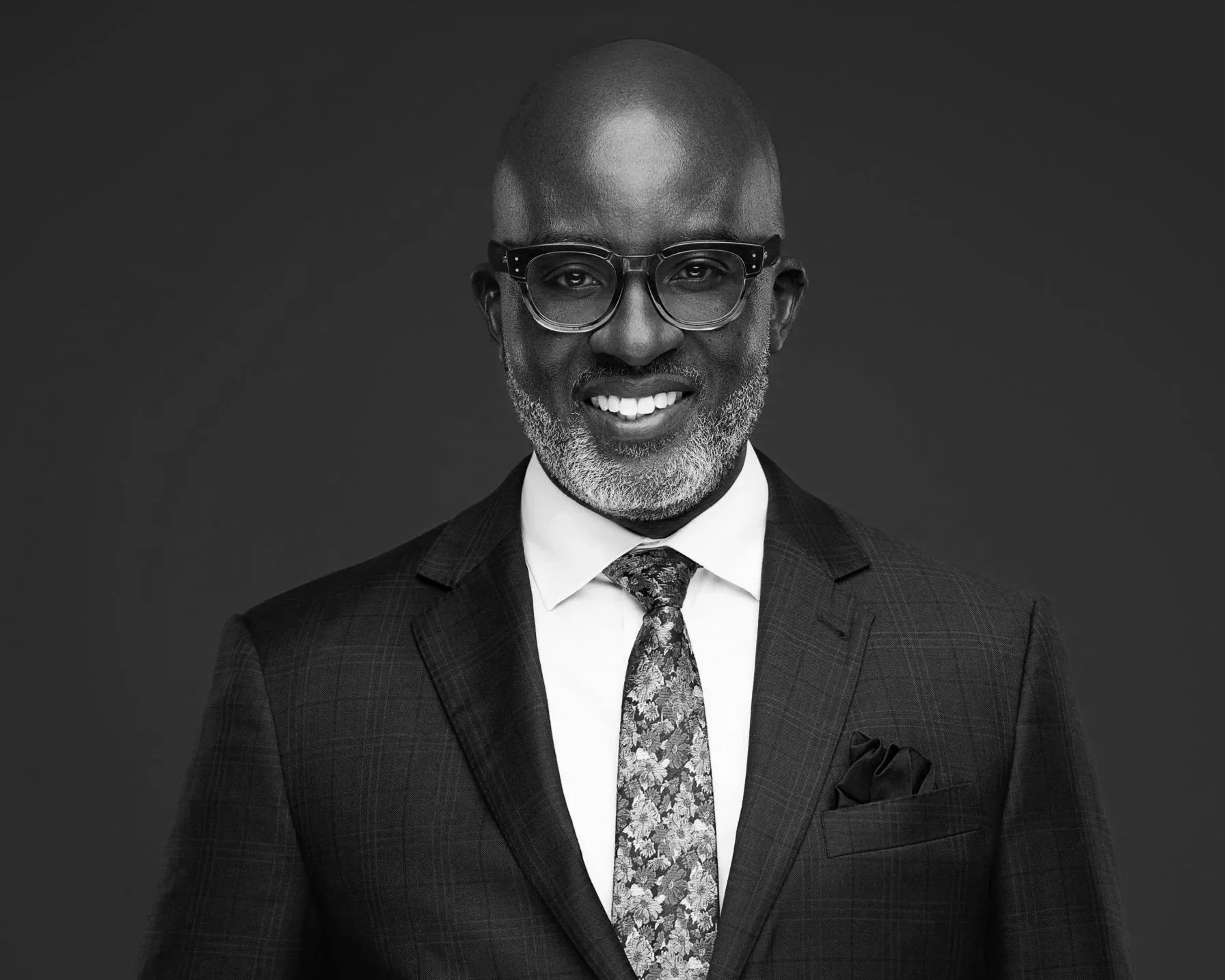 a middle aged, black man, with glasses in a suit and tie