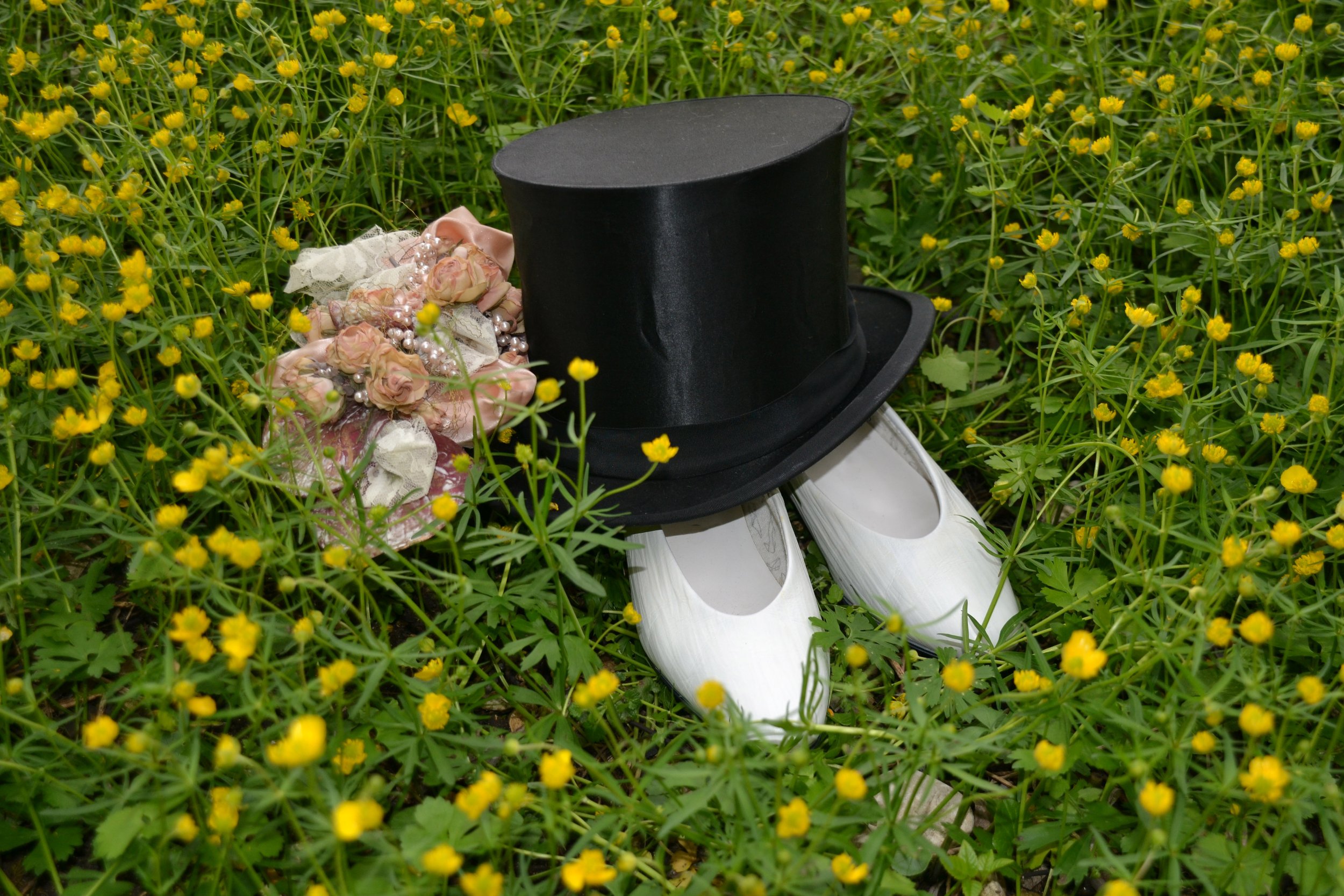 Schwarzer Zylinderhut, weiße Pantoffeln, Blumen und Perlen auf den Boden im Feld mit kleinen gelben Blumen, Hochzeitsacessoirs