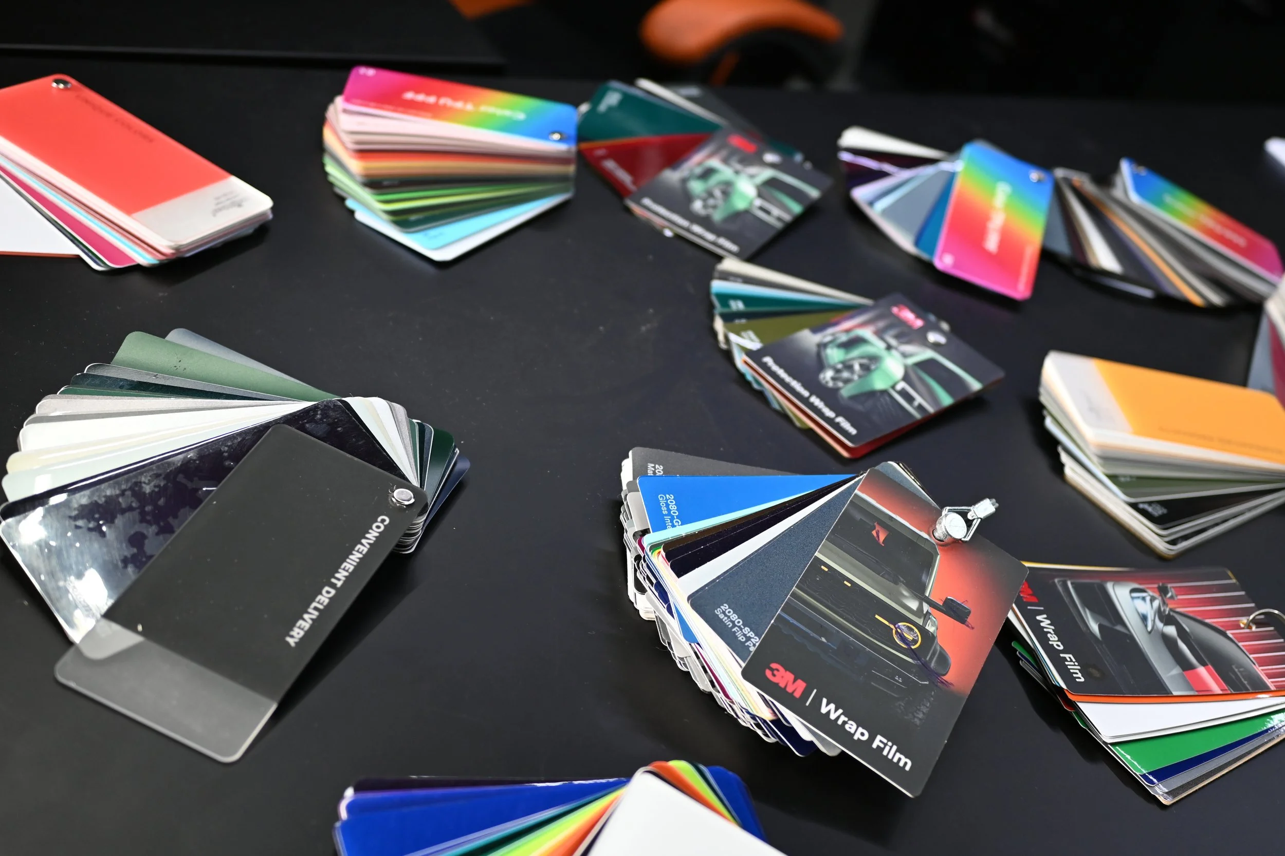 Multiple color sample and print film swatches spread out on a flat black surface