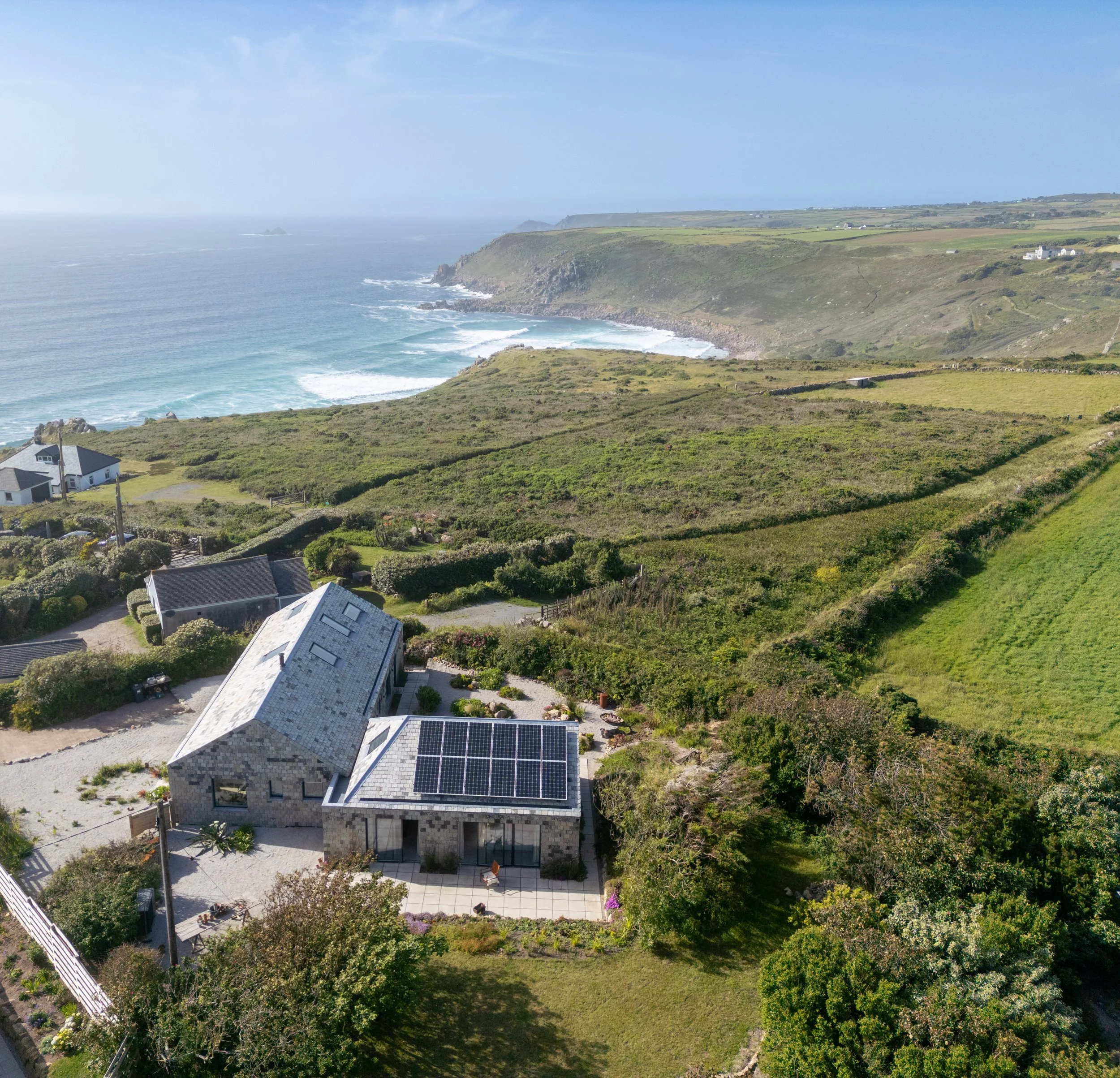   Rather than competing with its dramatic setting, the architecture is deliberately restrained. Reclad in reclaimed Delabole slate, the building exists with a patina already earned. Weathered greys are punctuated by warm ferrous tones, allowing the h