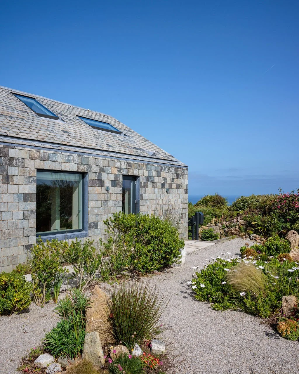   Outside, a traditional Cornish hedge shelters a courtyard planted with agaves, aloes and other species able to thrive in the harsh maritime climate, surrounded by Cornish granite gravel.   