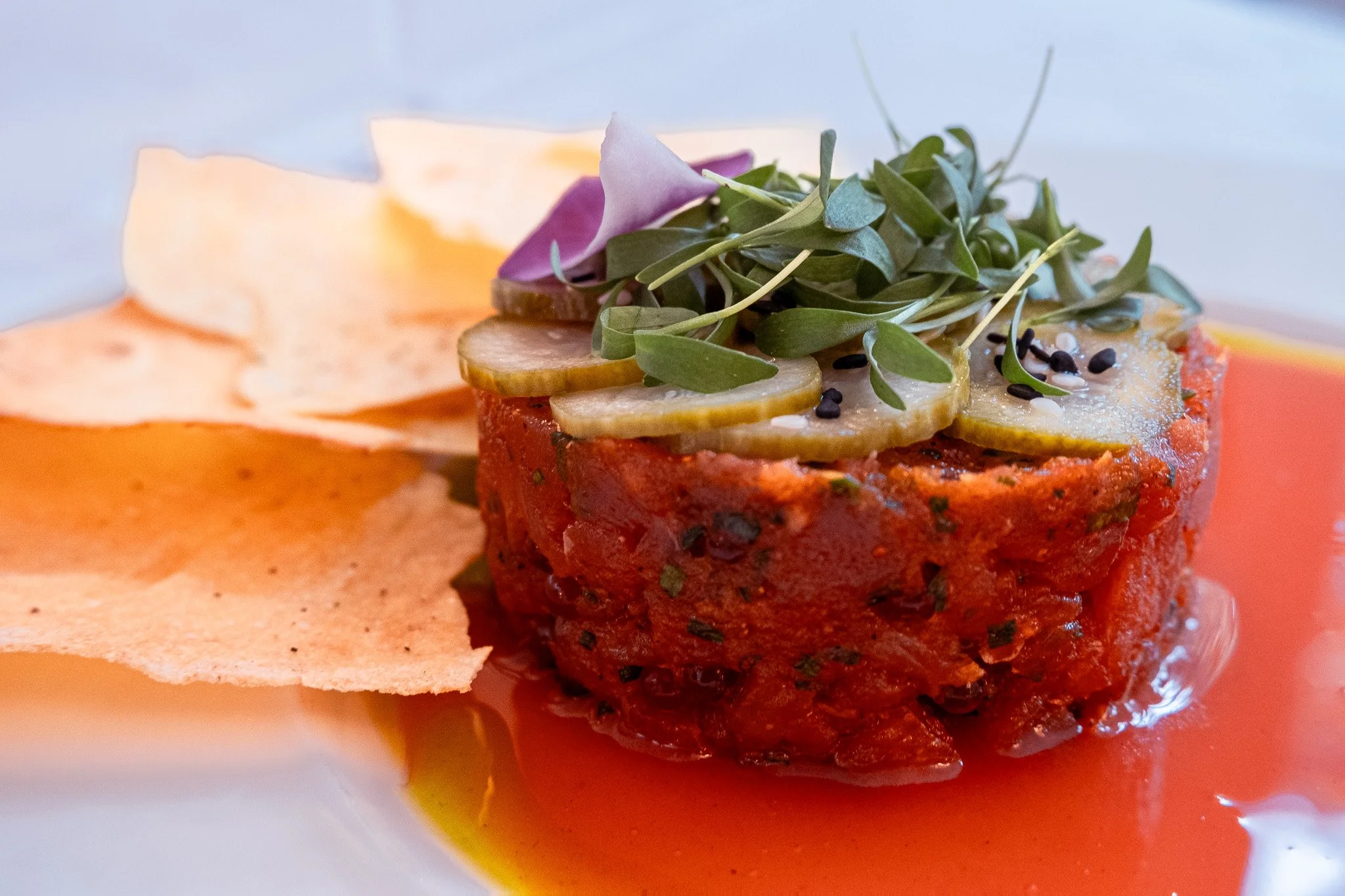 Elevate your table with our Yellowfin Tuna Crudo. Clean, fresh Yellowfin Tuna, nduja spices, and trout roe meet pickled Persian cucumber and sesame, all kissed by a bright blood orange consomm&eacute;. Crispy carasau flatbread completes this stunning