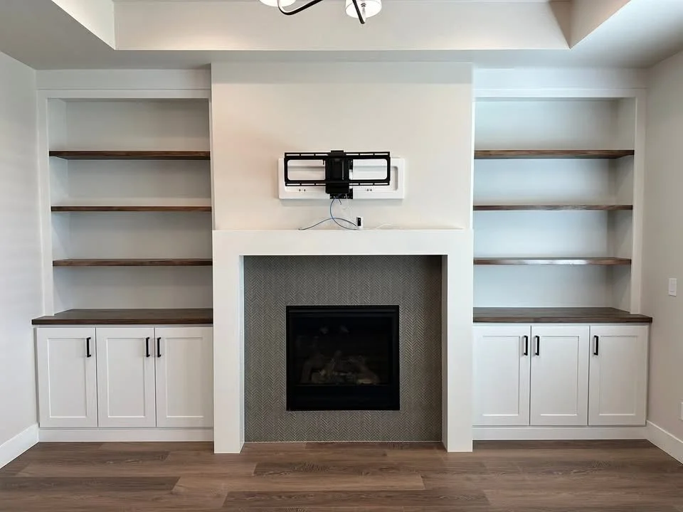 Custom built-in fireplace wall with white shaker cabinets, walnut floating shelves, and a modern tile fireplace surround in Nampa, Idaho.