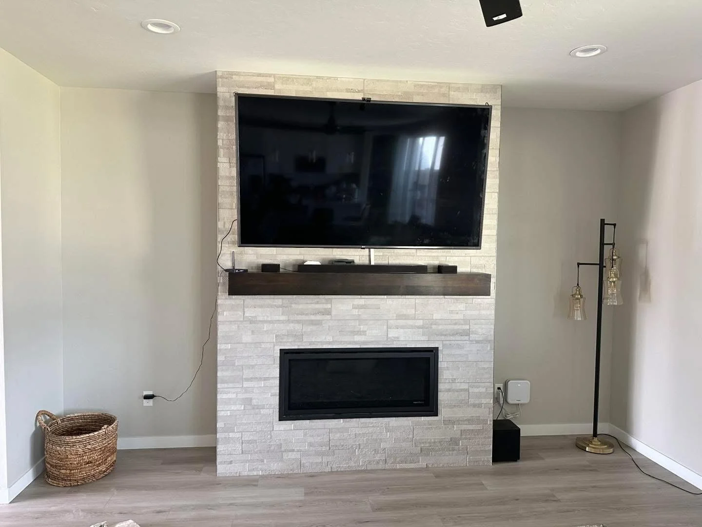 Contemporary stacked stone fireplace feature wall with a floating wood mantel in a Meridian, Idaho living room.
