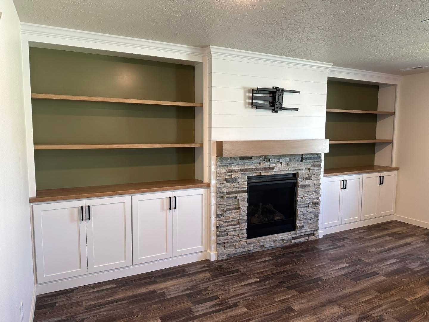 Custom living room built-ins surrounding a stone fireplace with floating shelves.