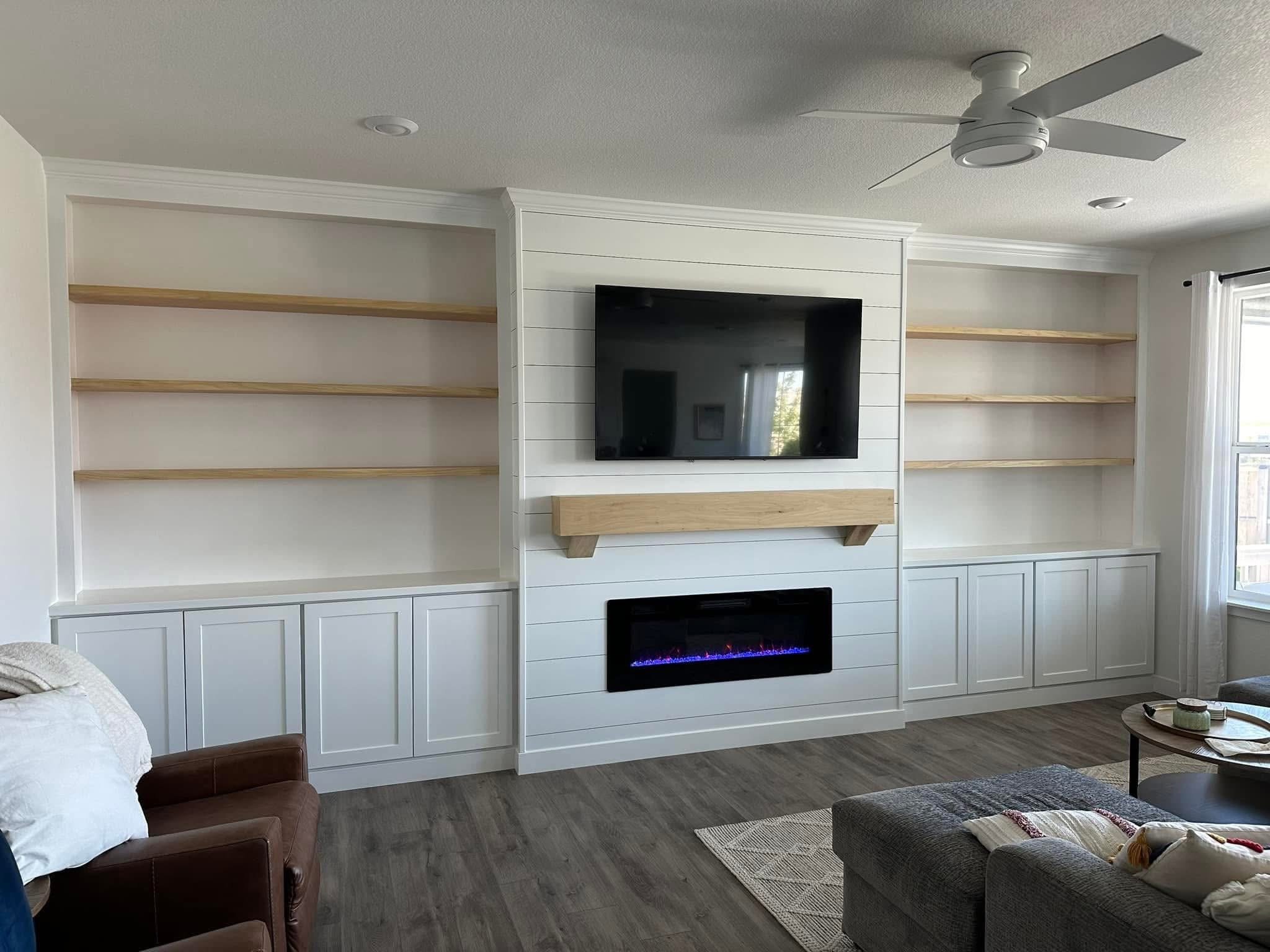 Modern fireplace built-ins with a white oak mantel, custom shelving, and white shaker cabinets in a Caldwell, Idaho living room.