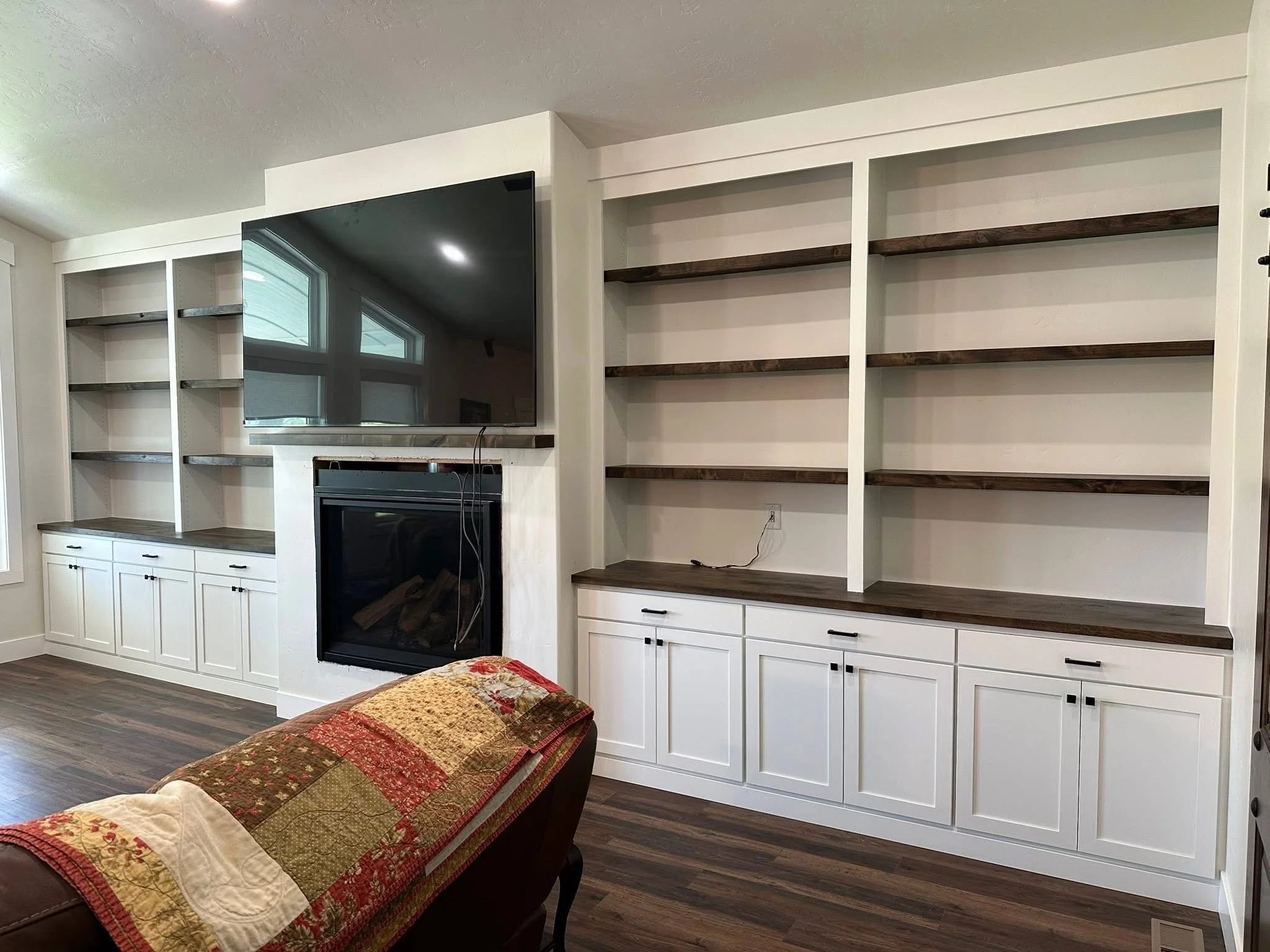 White shaker entertainment center with custom built-in cabinets, open shelving, and fireplace surround in Wilder, Idaho.