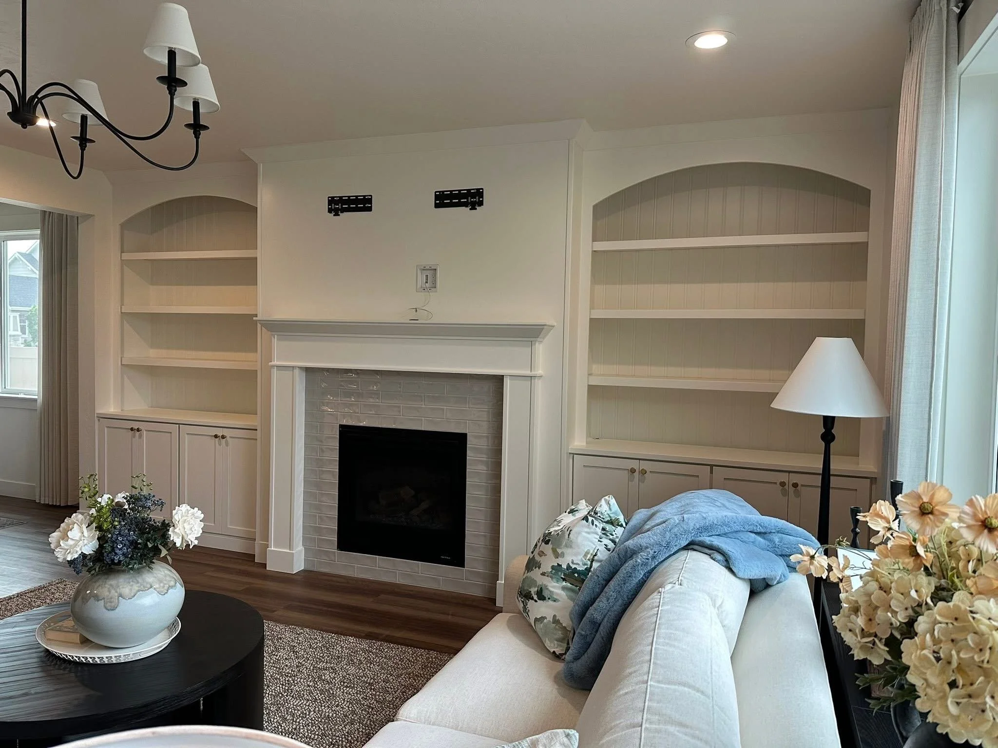 Custom white built-in bookshelves with arched openings and a fireplace surround in a professionally staged living room in Star, Idaho.