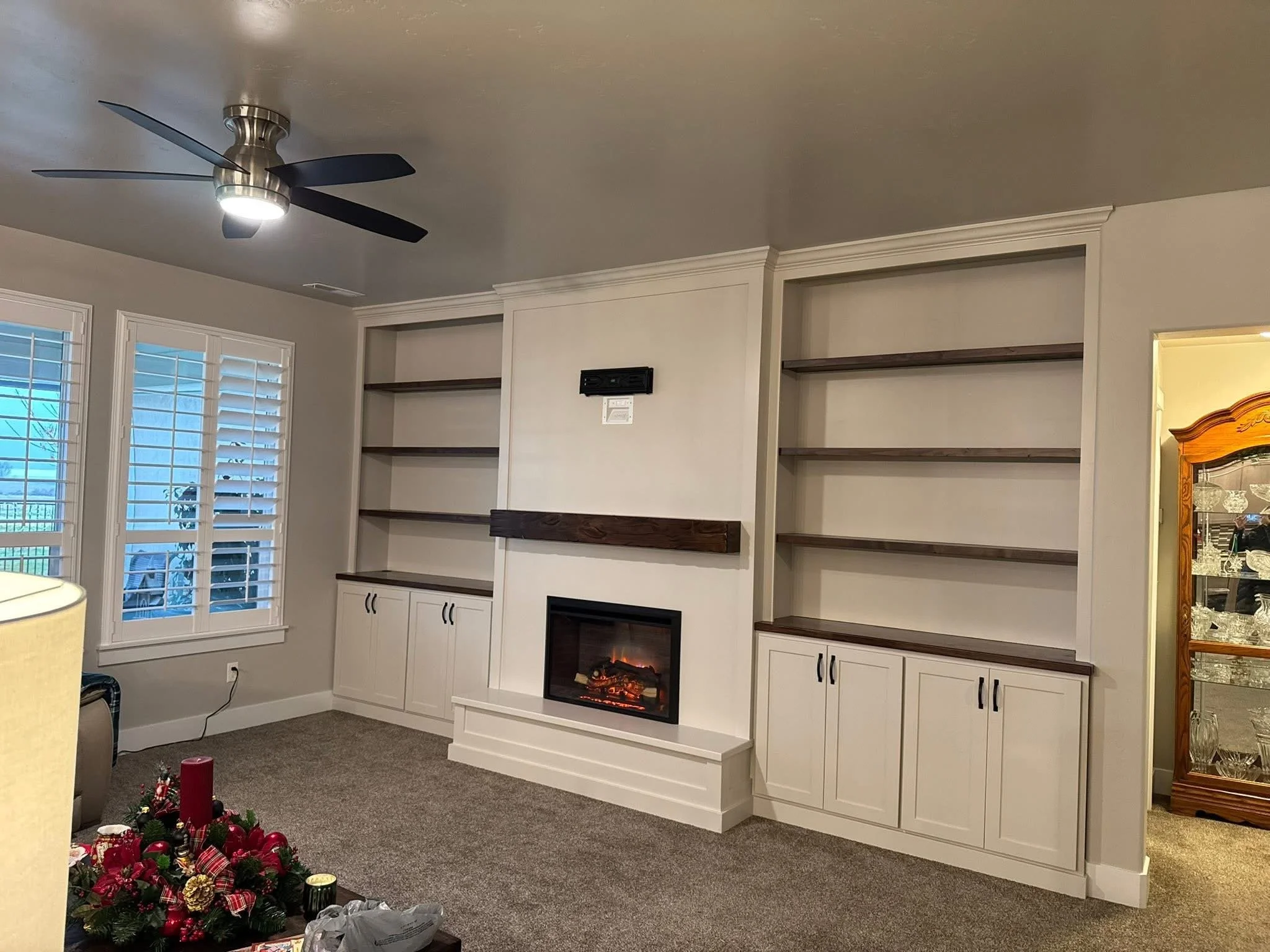 Painted built-in cabinets with dark wood shelves, a custom fireplace surround, and an electric fireplace in a Meridian, Idaho home.