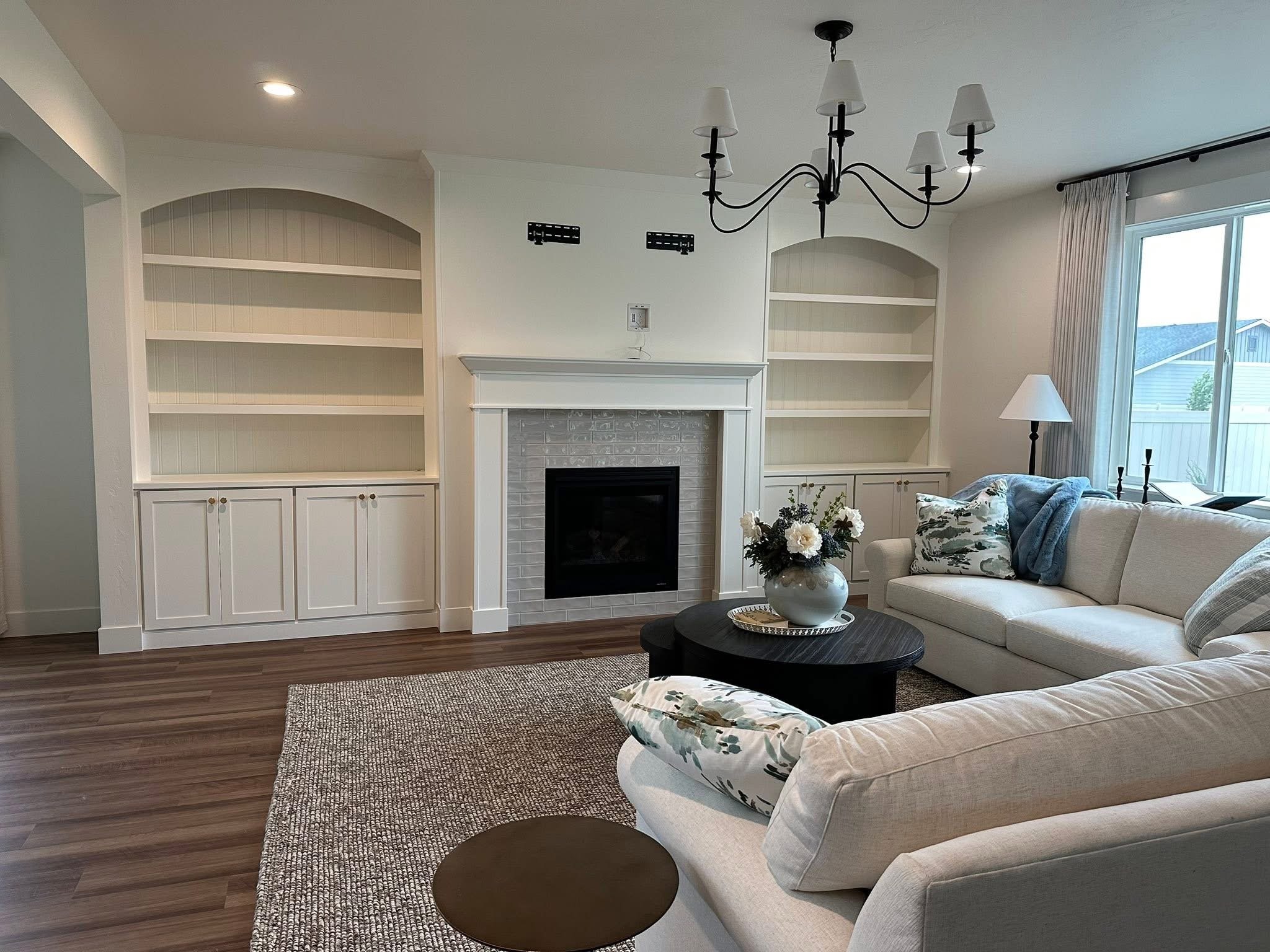 White built-in shelving and cabinets surrounding a fireplace in a bright, modern living room in Star, Idaho.