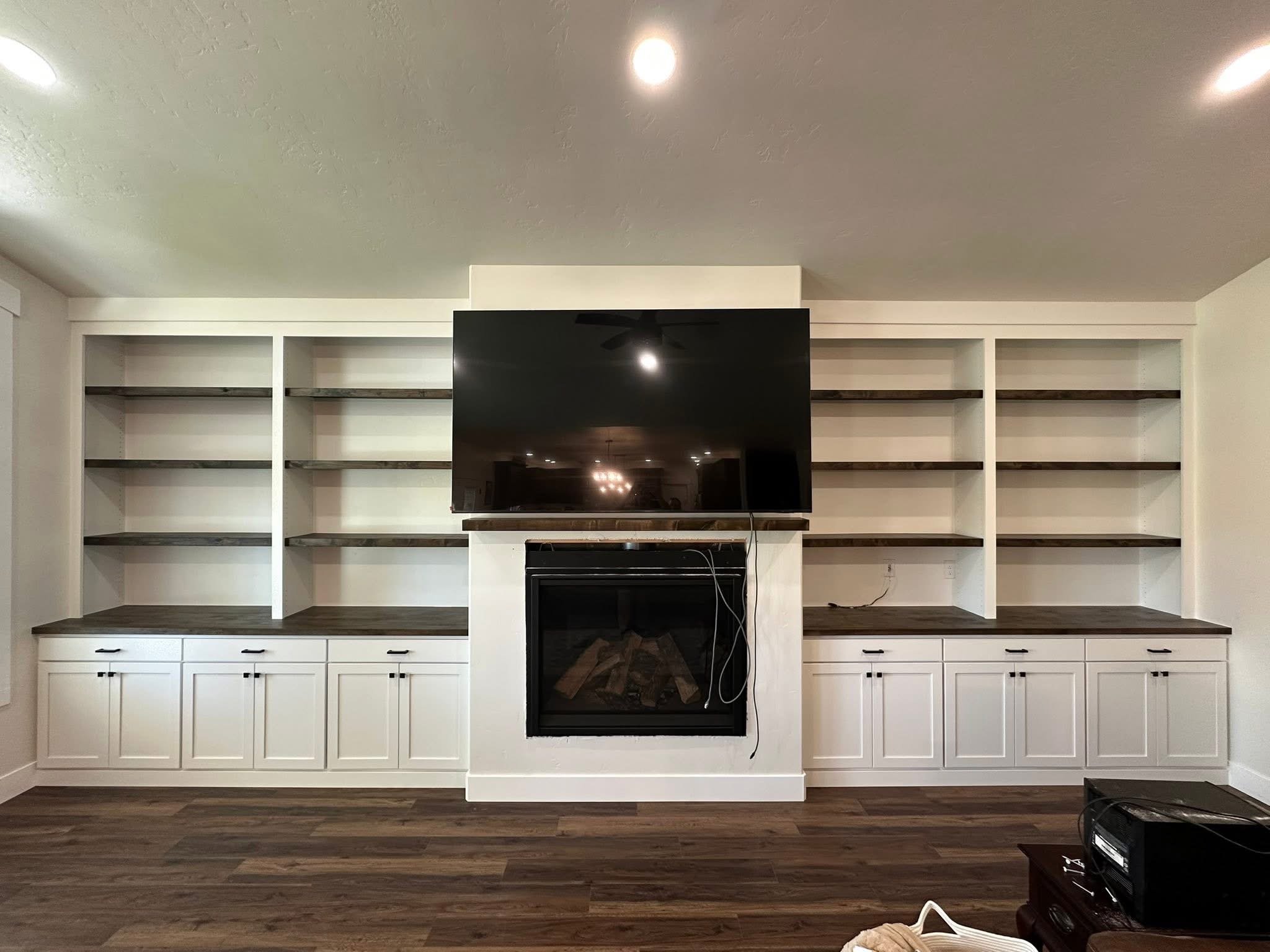 Custom living room built-in cabinets with open shelving surrounding a fireplace and TV in Wilder, Idaho.