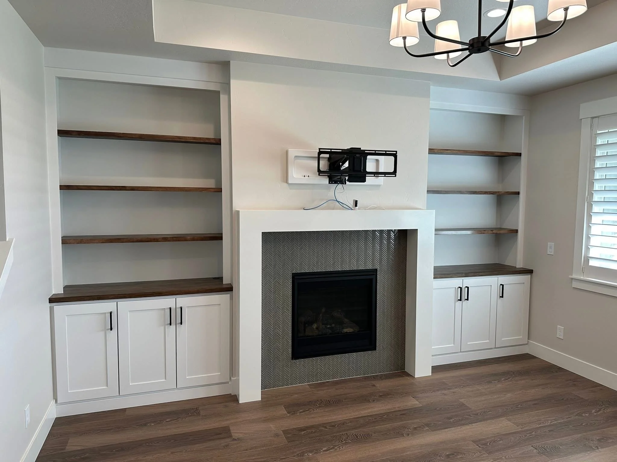 White built-in cabinets with stained walnut shelves surrounding a modern fireplace in a custom Nampa, Idaho home.