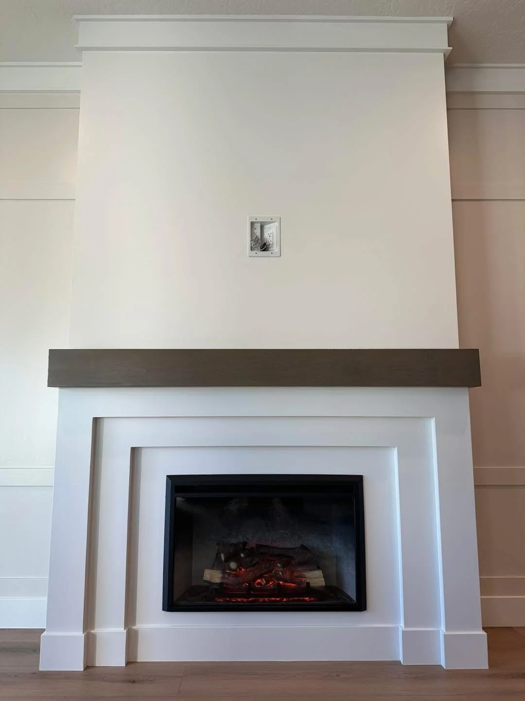 Modern fireplace with decorative trim surround and a stained floating wood mantel in a custom Meridian, Idaho home.