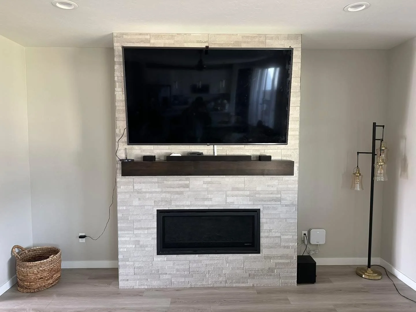 Modern stacked stone fireplace wall with a floating wood mantel and TV installation in a custom Meridian, Idaho home.