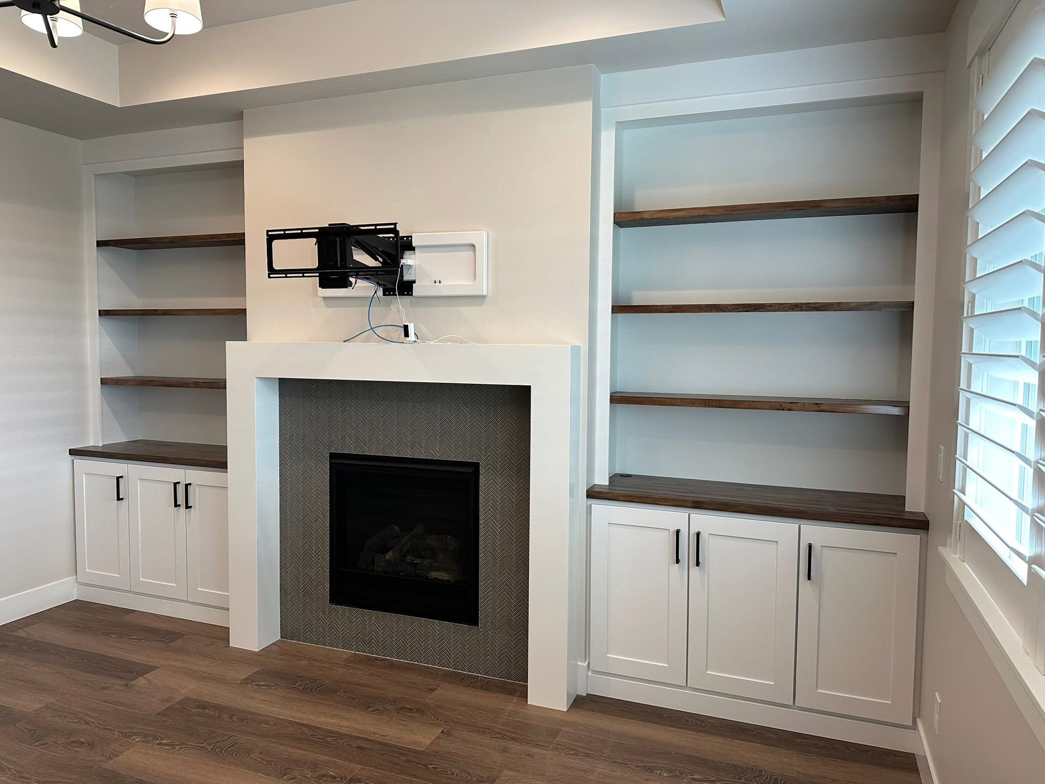 Custom fireplace built-ins with white shaker cabinetry, floating walnut shelves, and a modern tile surround in Nampa, Idaho.